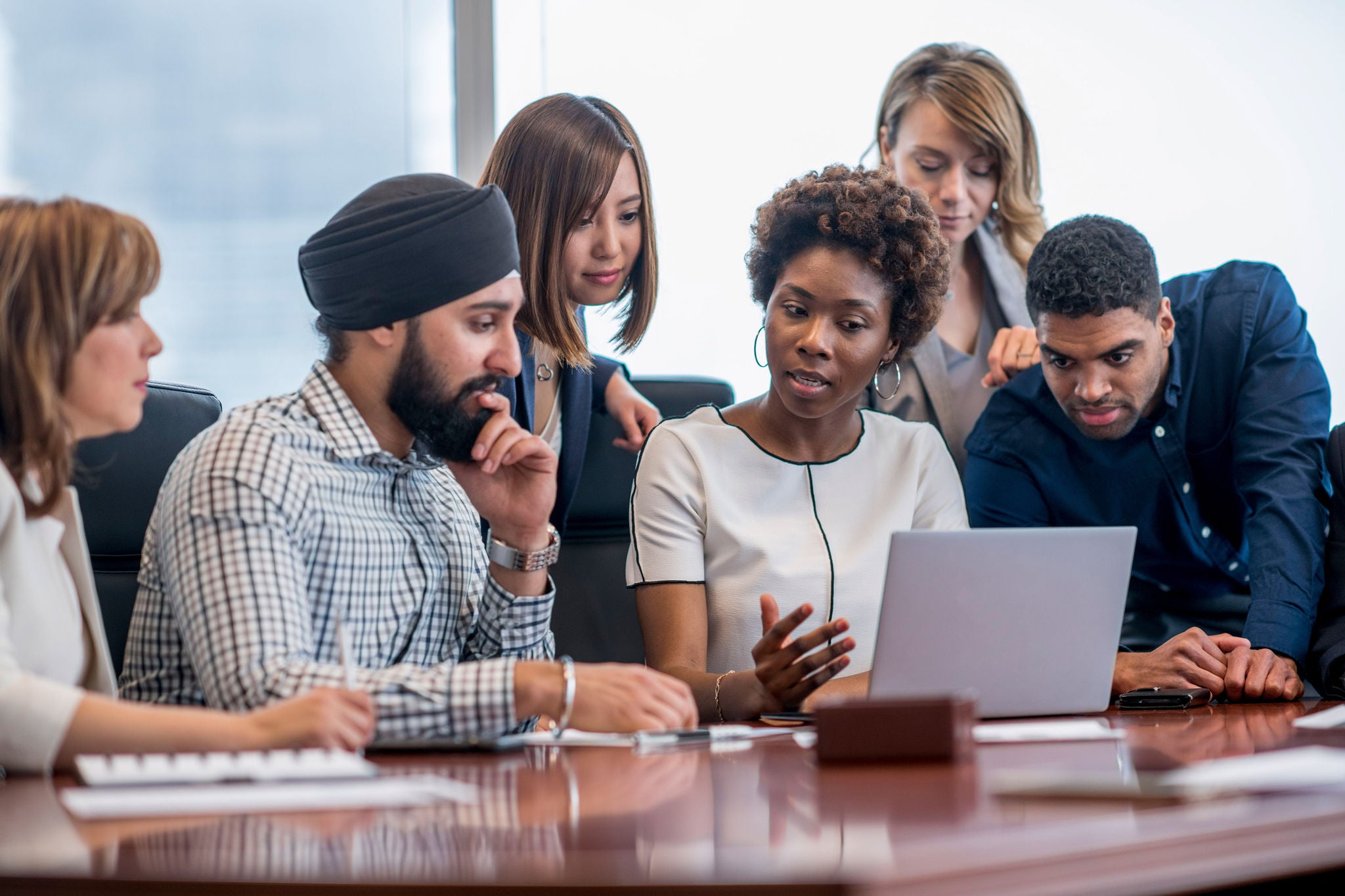 Professionals working together around a laptop during a collaborative business discussion.