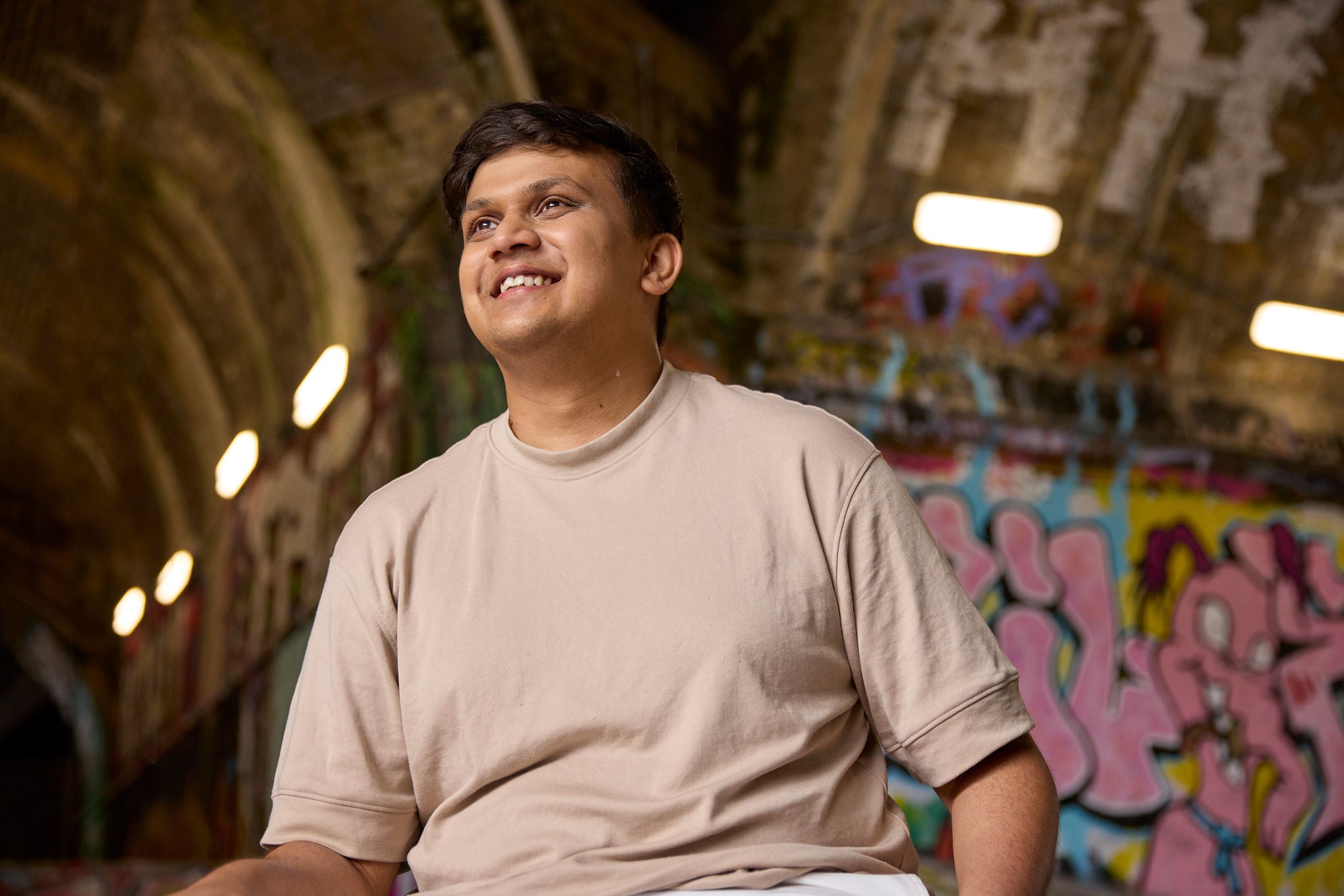 Person standing in front of a wall with graffiti