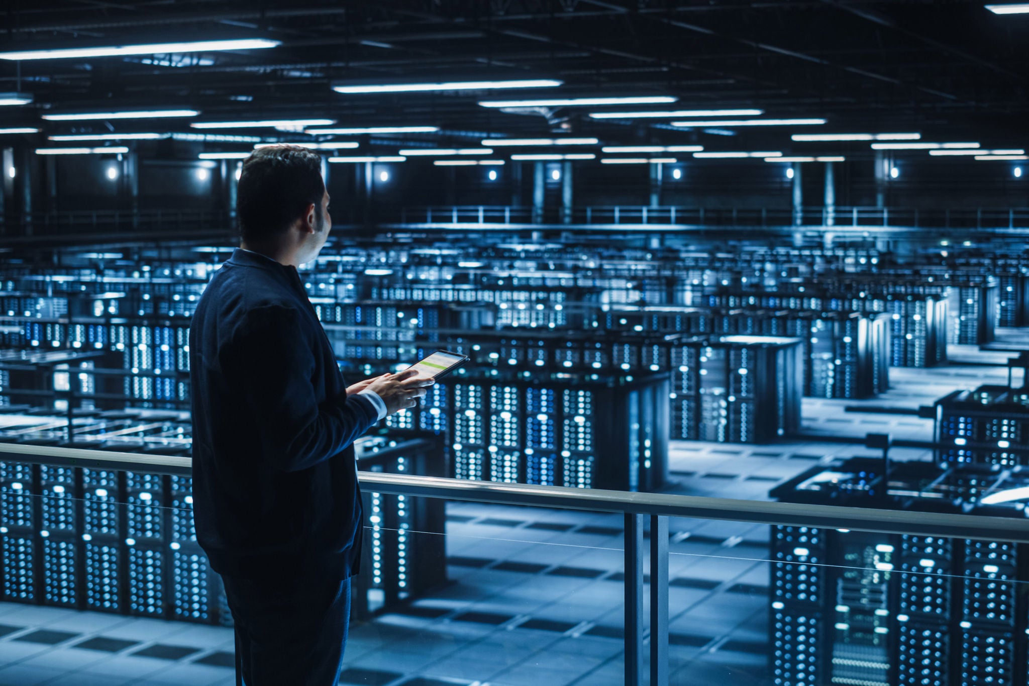 Man viewing server racks in a data center with a tablet