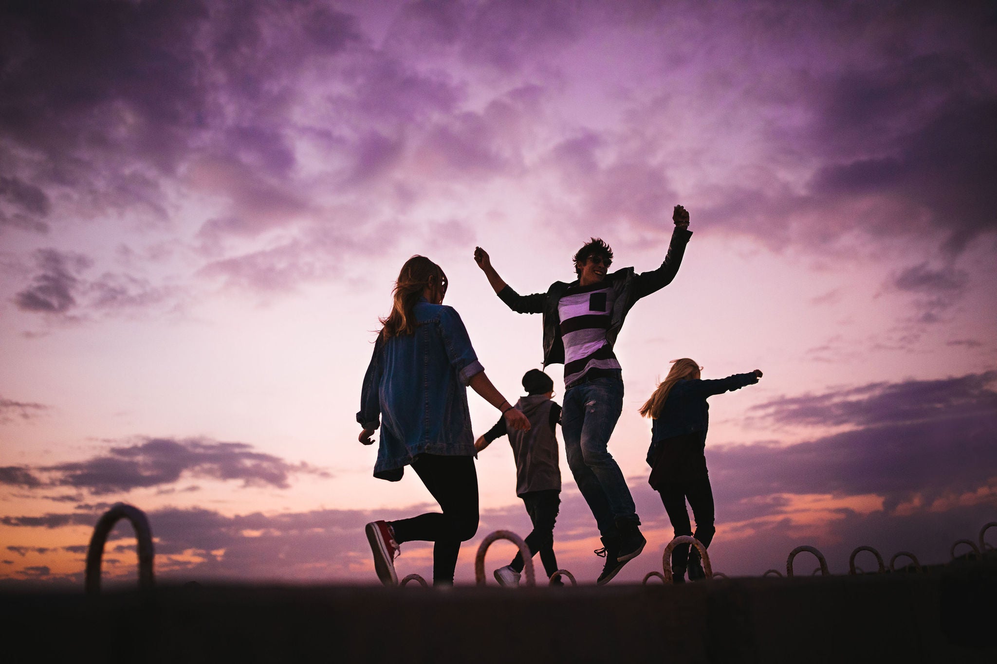Group of people jumping around outdoors at sunset