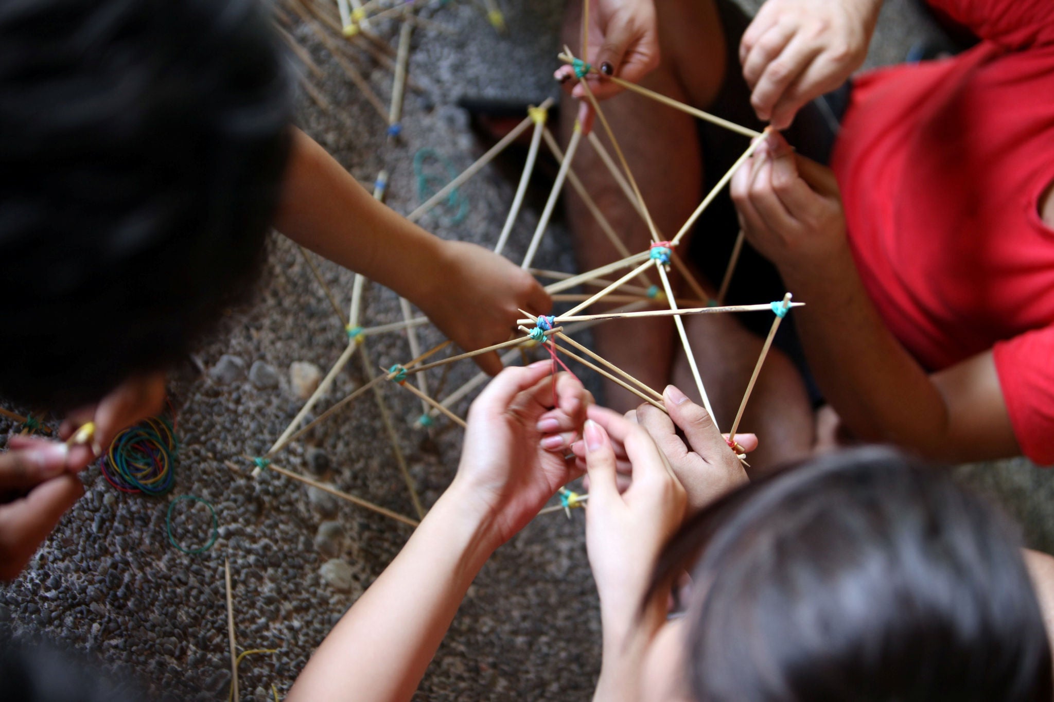 High angle photograph of friends making model with rubber bands and sticks