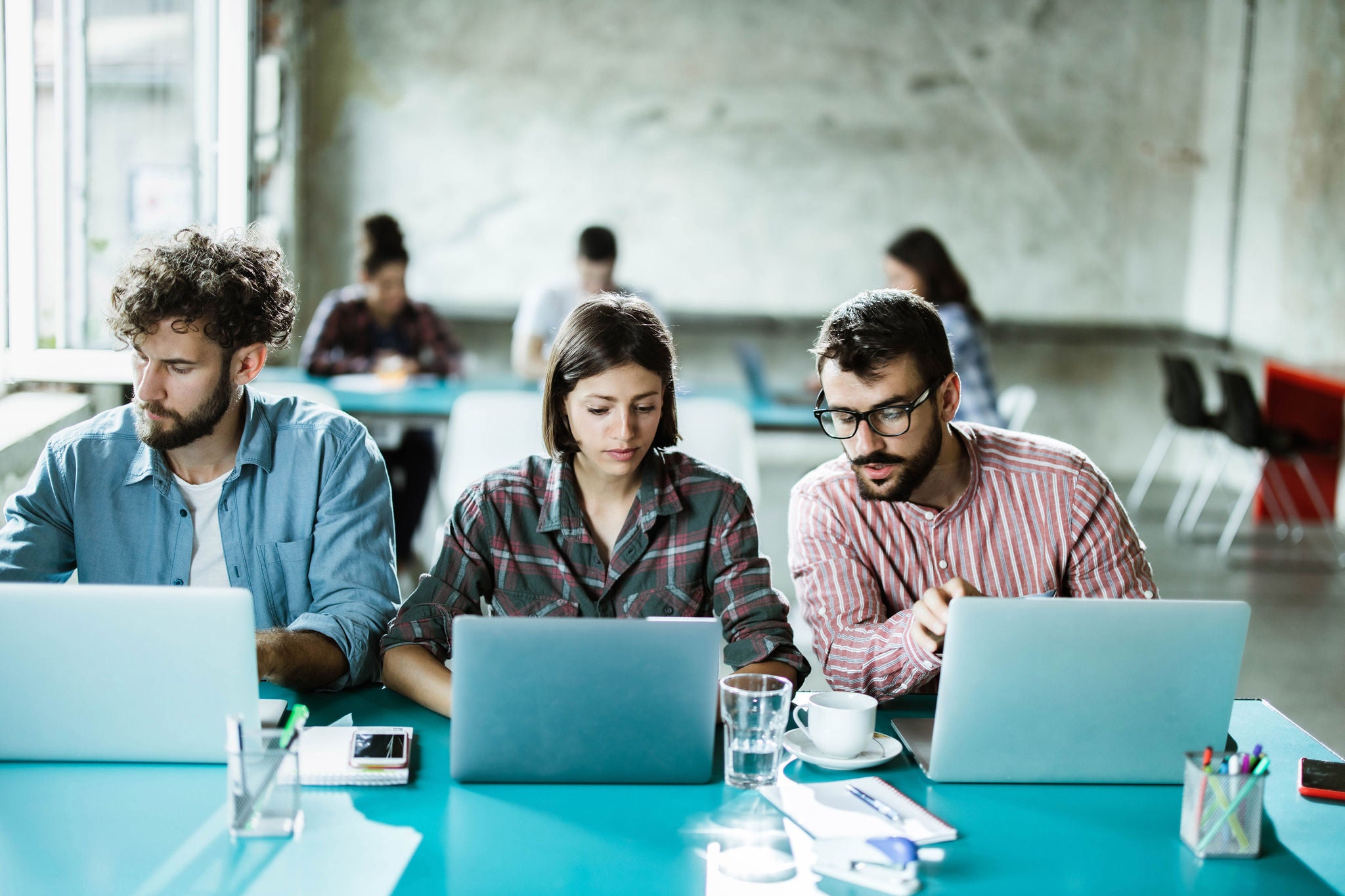 Team of young programmers cooperating while working on computers in the office. Copy space.