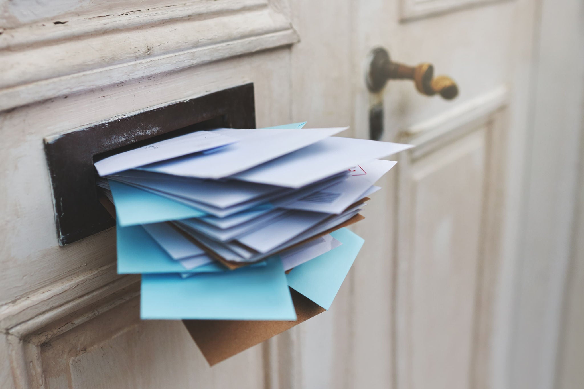 Eine Haustür mit einem überfülltem Briefkasten.