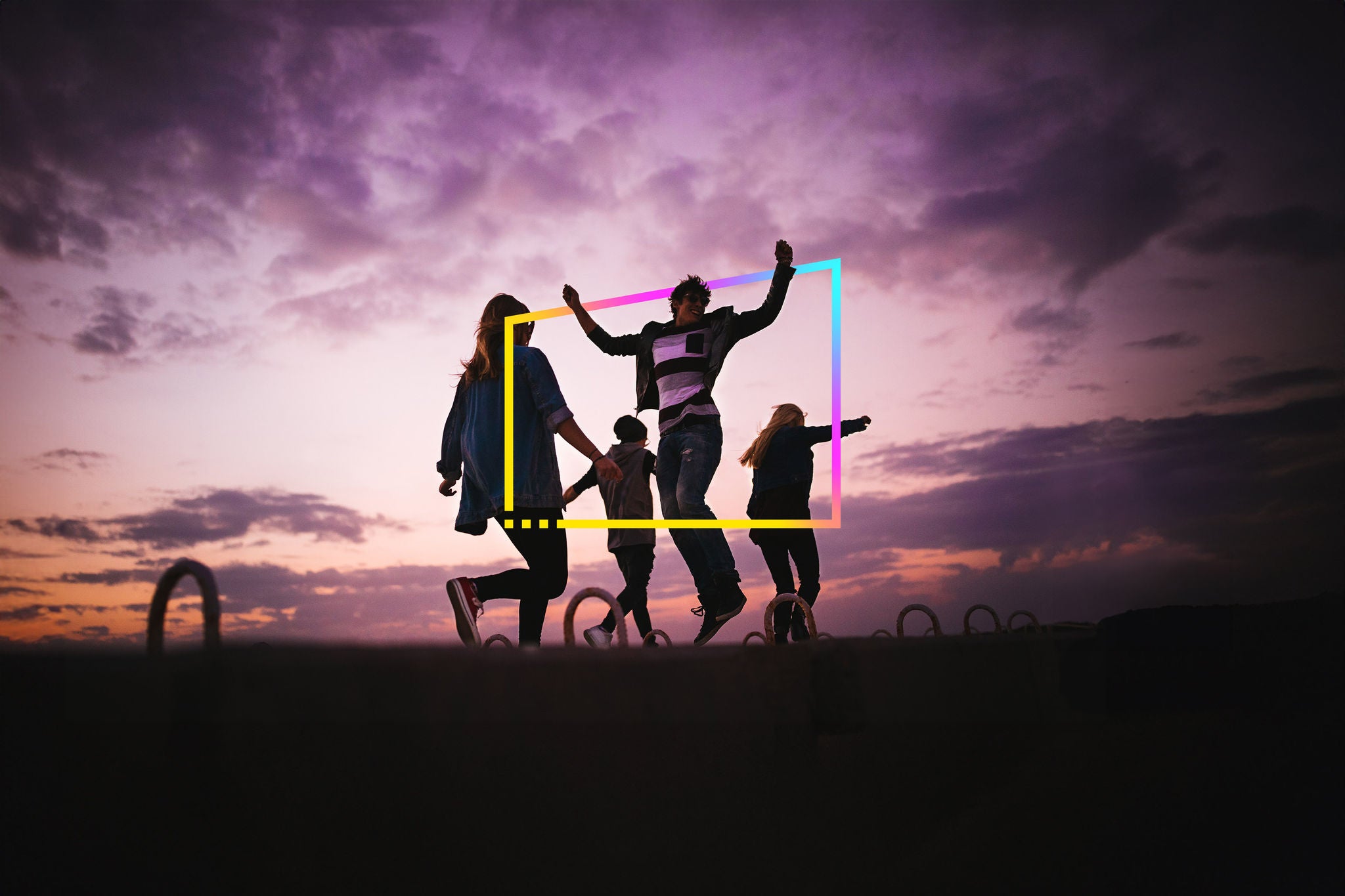 group of people jumping around outdoors at sunset
