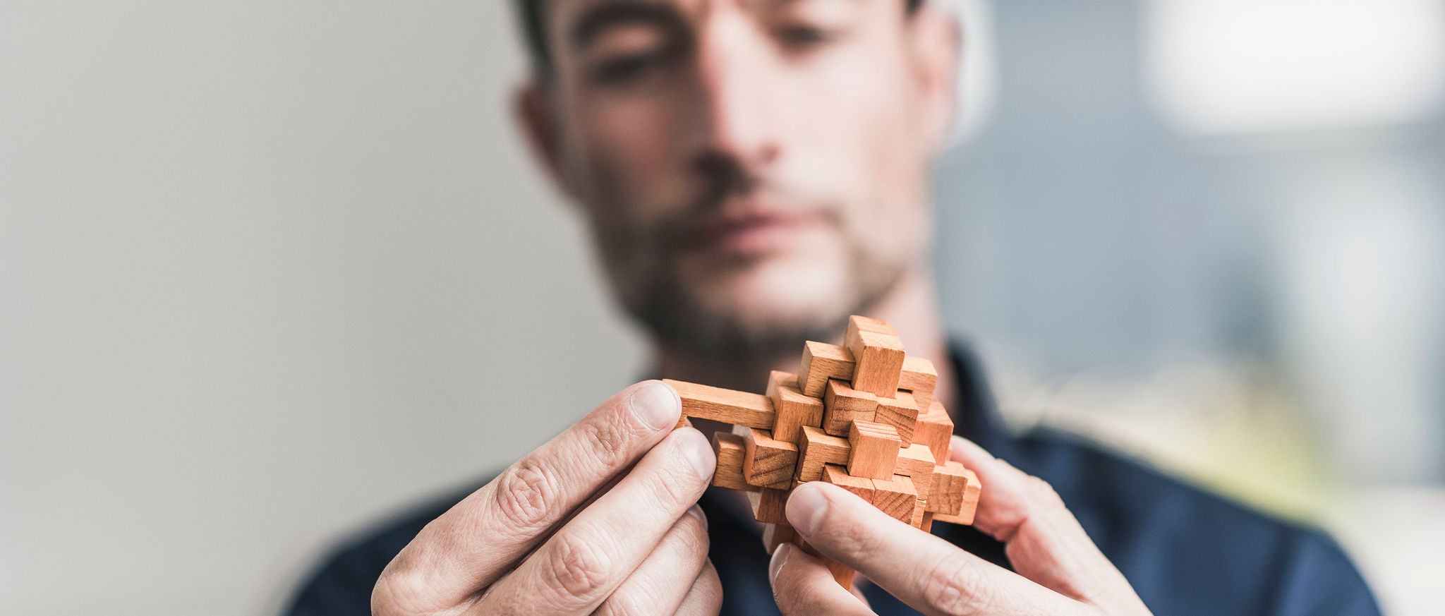Mature man sitting in office assembling wooden cube puzzle