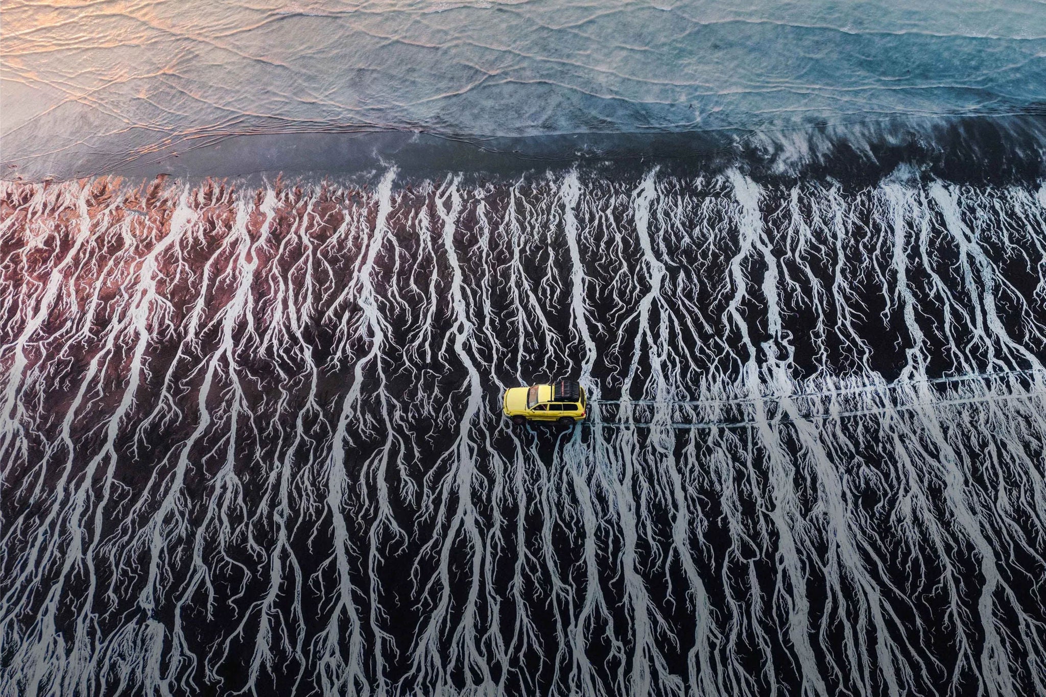 Aerial shot of car driving on the beach