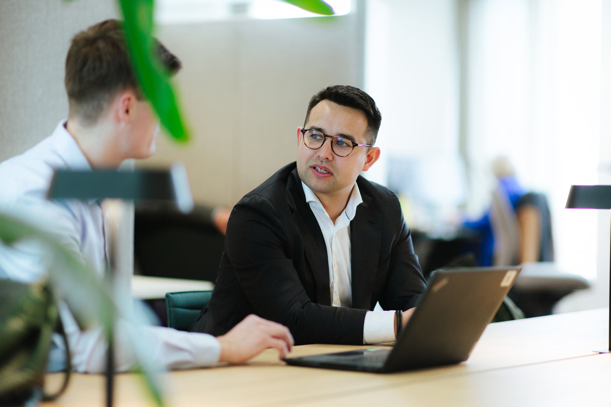 Professionals discussing work together at laptop in modern office