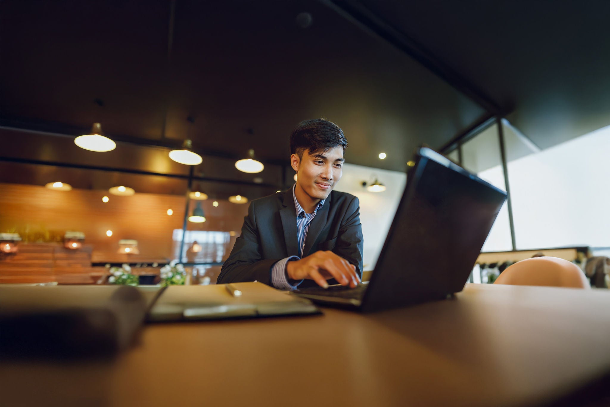 Young asian man looking at laptop in brown coffee shop