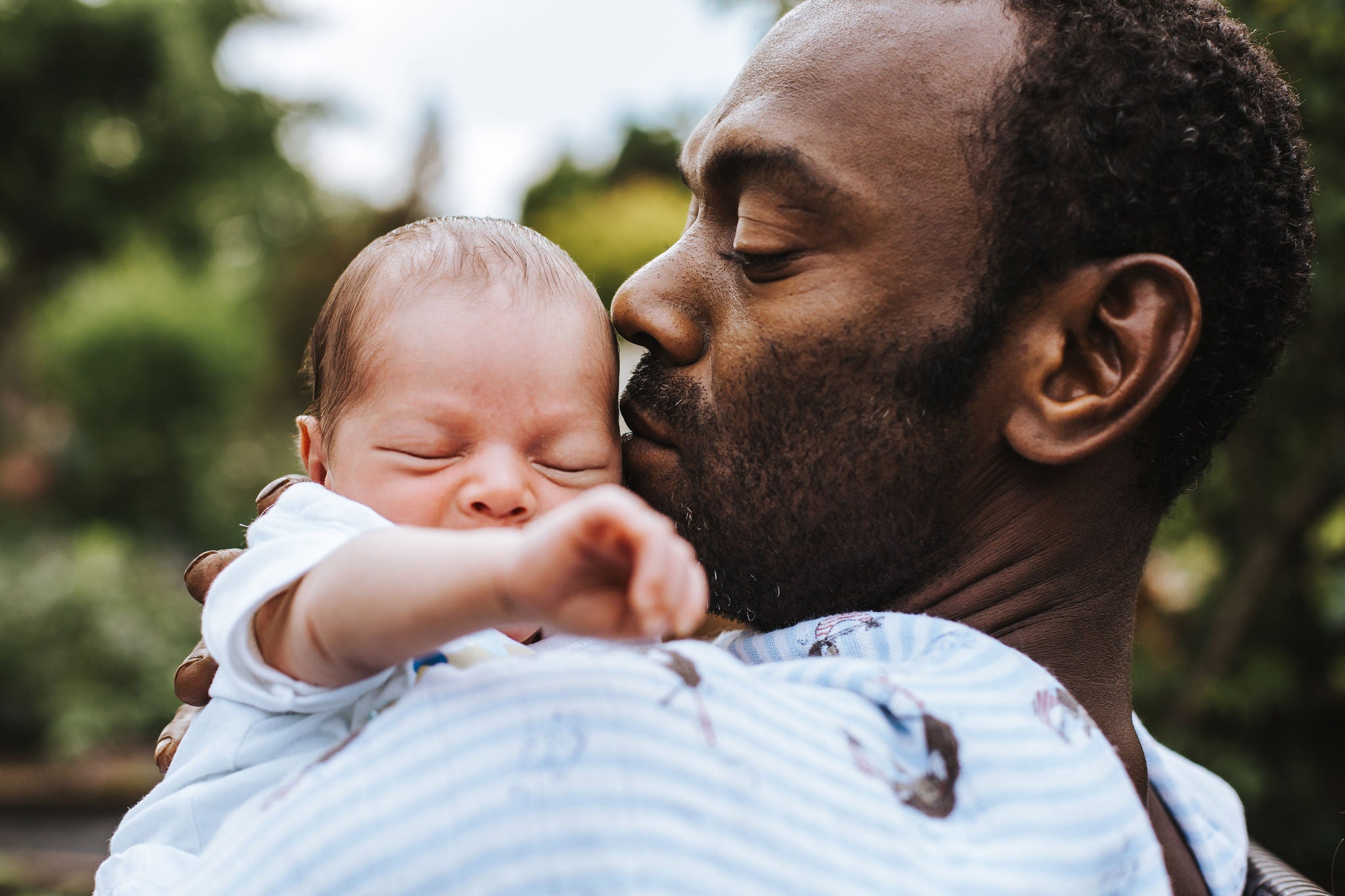 black father kissing his mixed race baby boy on the cheek