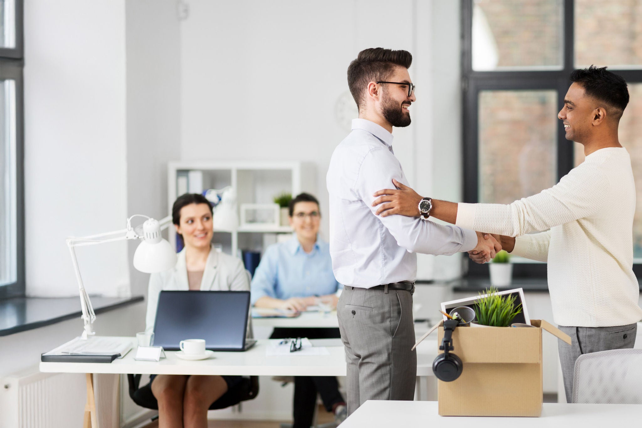 Business, new job and corporate concept - male employee meeting colleague and shaking his hand at office
