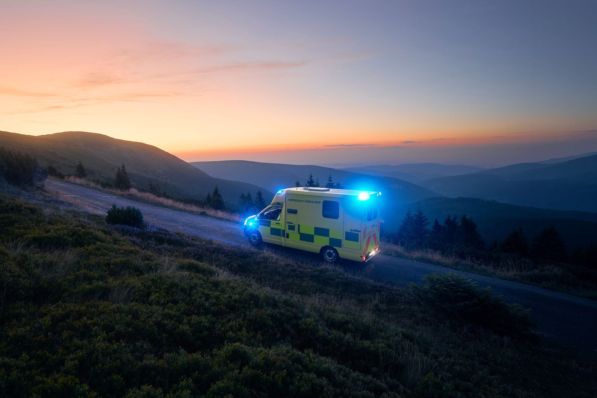 Ambulance car of emergency medical service mountain road against sunrise