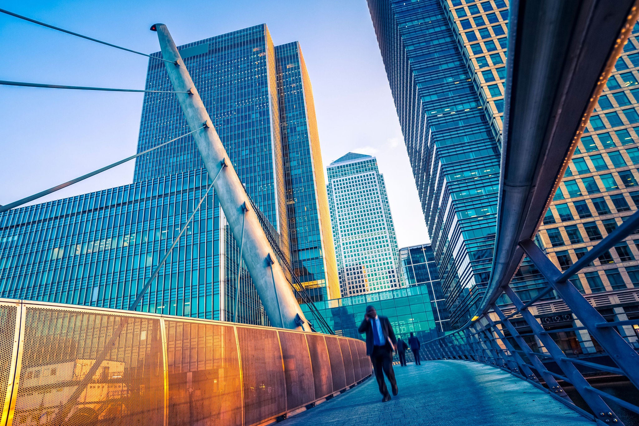 Landscape photograph of a businessman walking on a contemporary bridge in Canary Wharf.