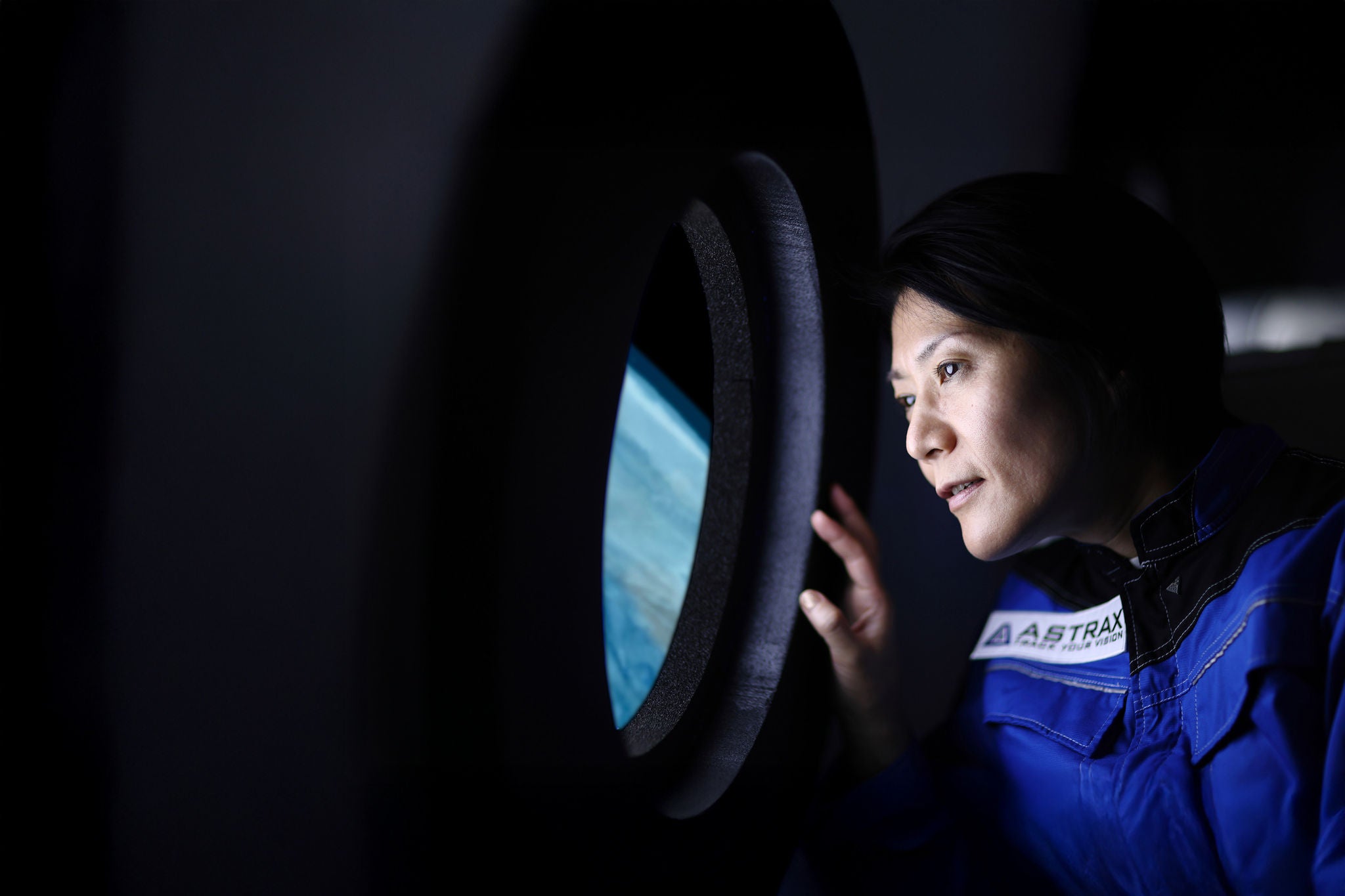 Ansicht der Erde durch ein Rundfenster im Inneren eines Raumschiffs.