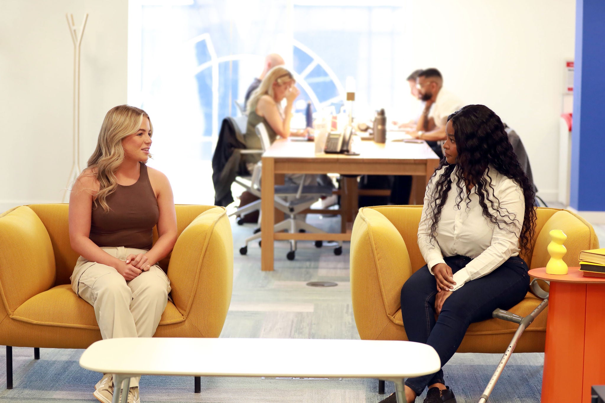 Two colleagues chatting on yellow chairs