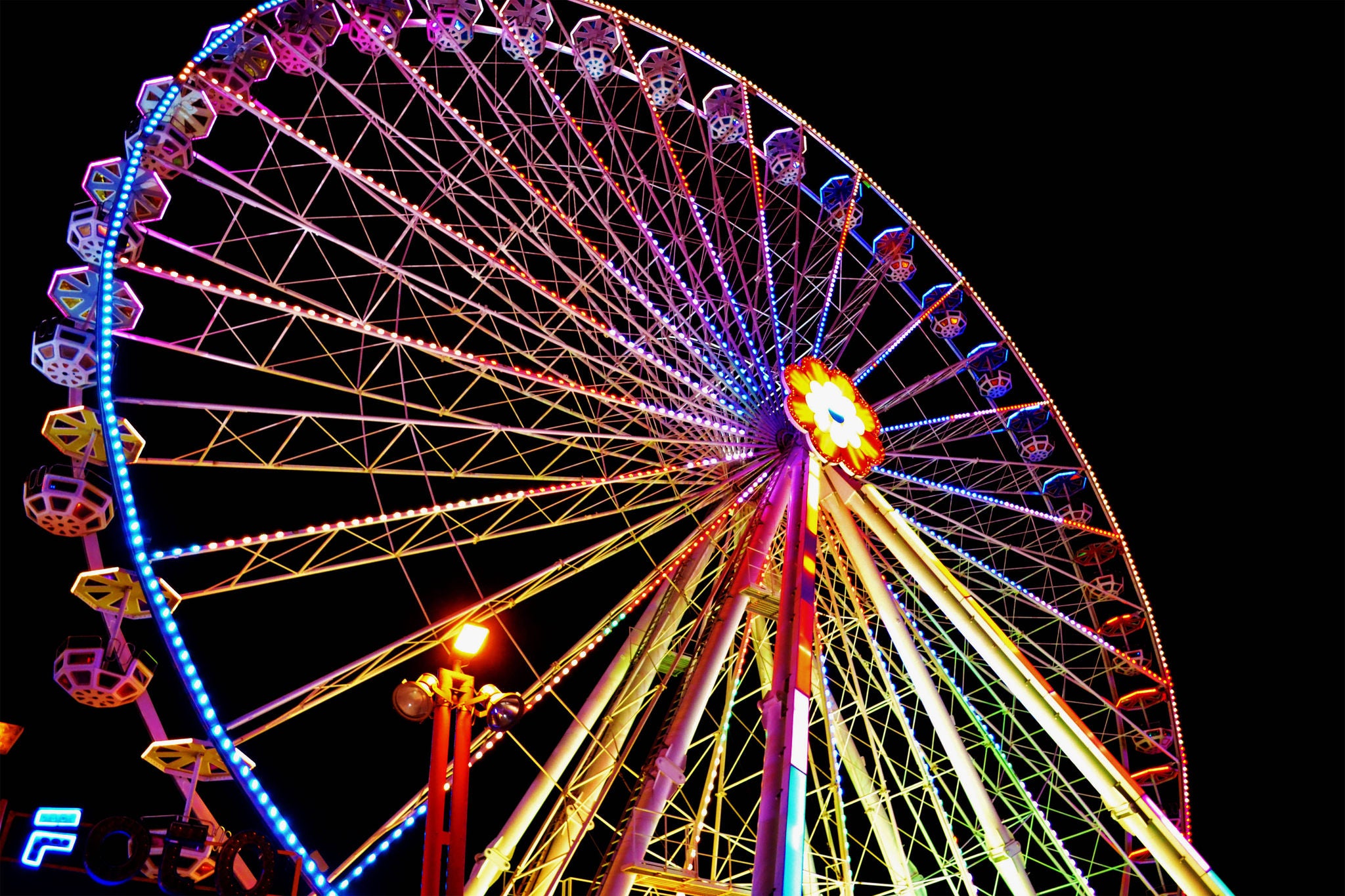 Vibrant Ferris wheel glowing with neon lights at night in a lively amusement park