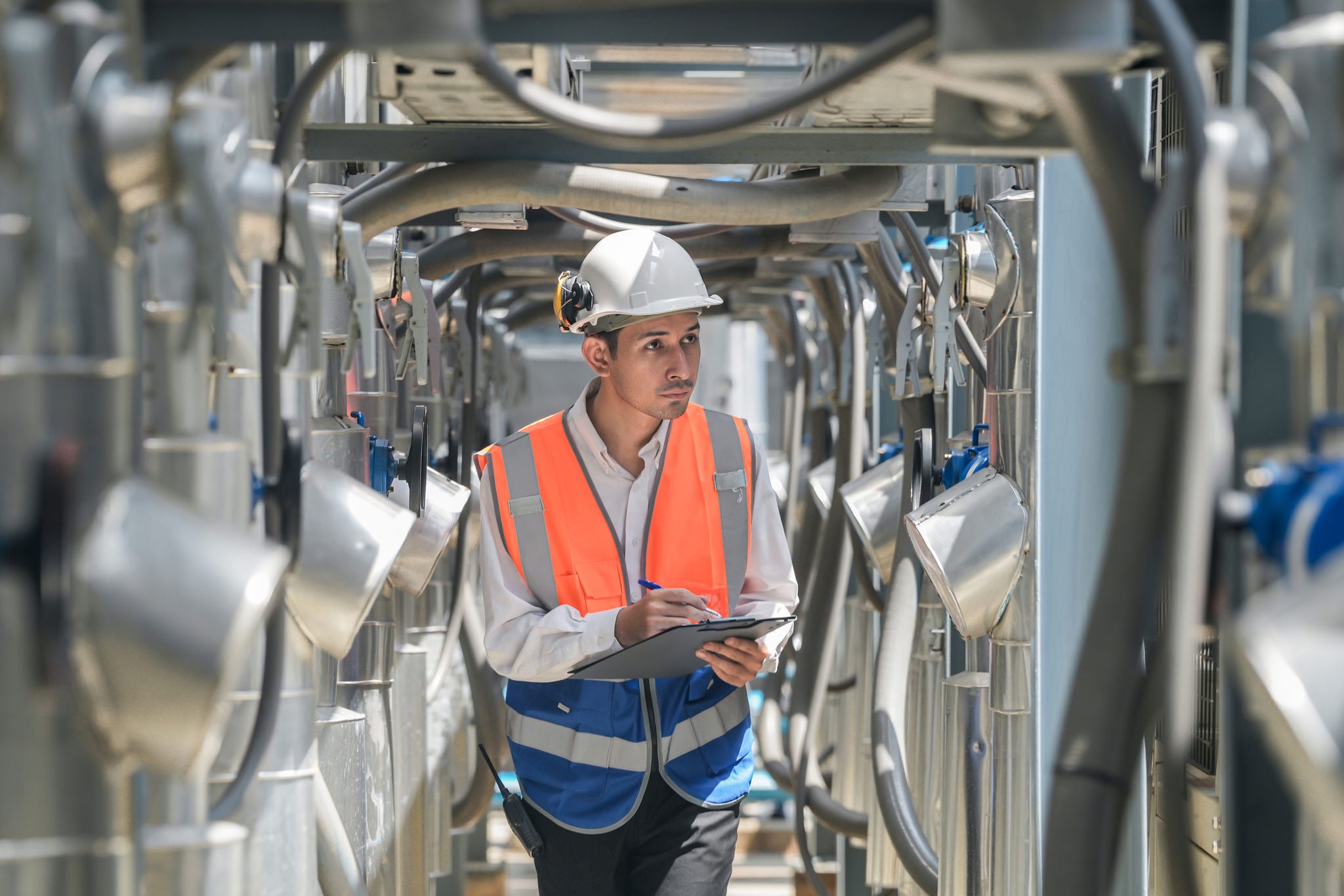 Engineers inspect gas and water pipes for power and cooling in industrial and building systems. workers in safety gear work seriously in oil and gas refining plant with pipes connecting to machinery.