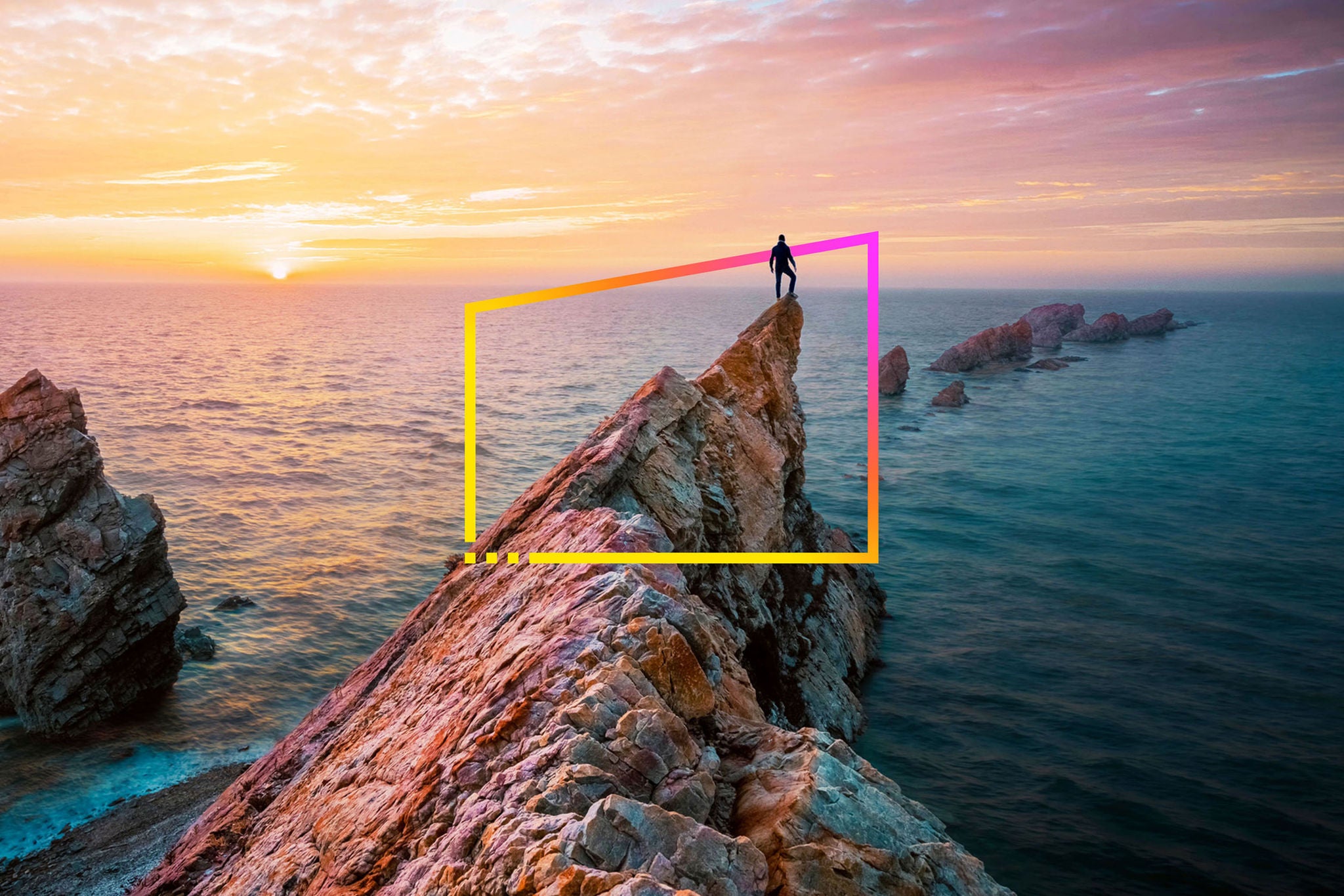 Man standing on rocky outcrop by sea watching sunset static