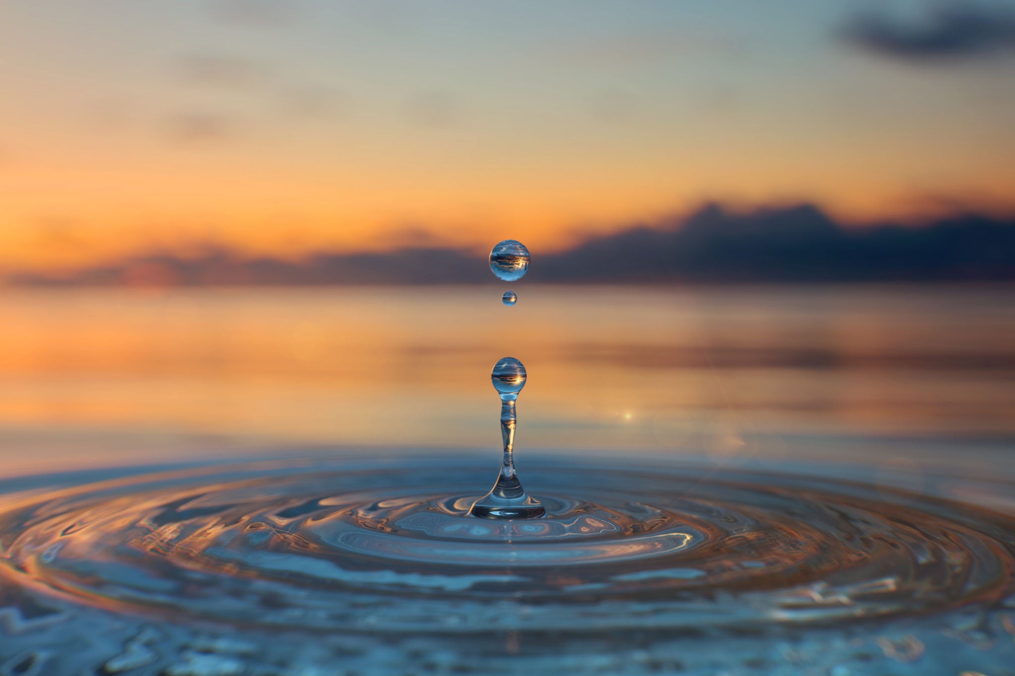 Clear Blue Water drop with circular waves on sunset background