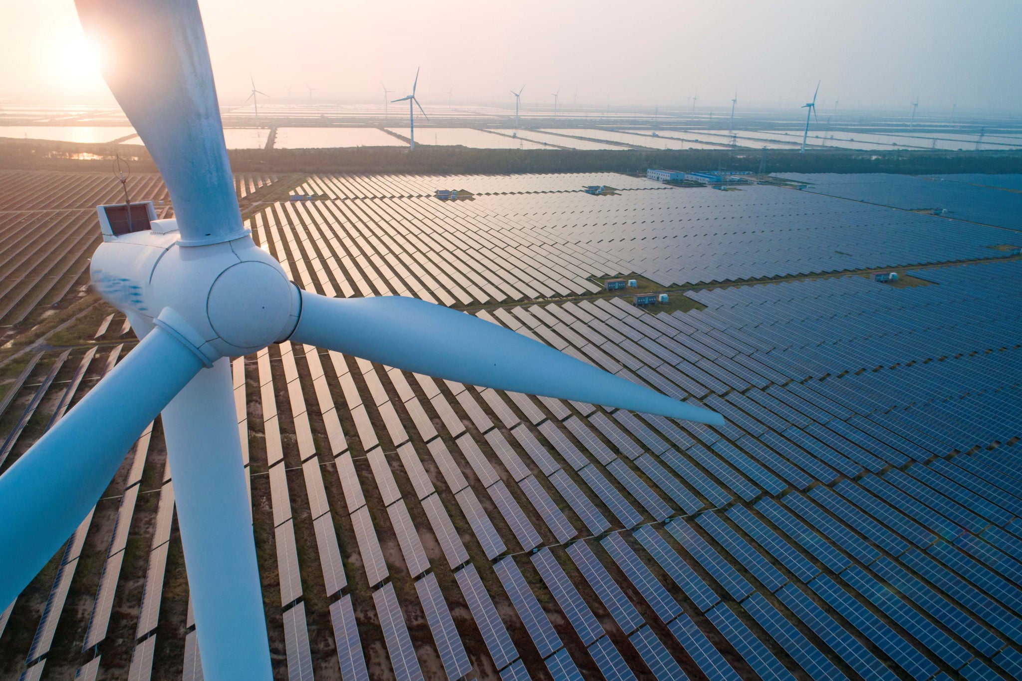 photo of a wind turbine over a solar farm