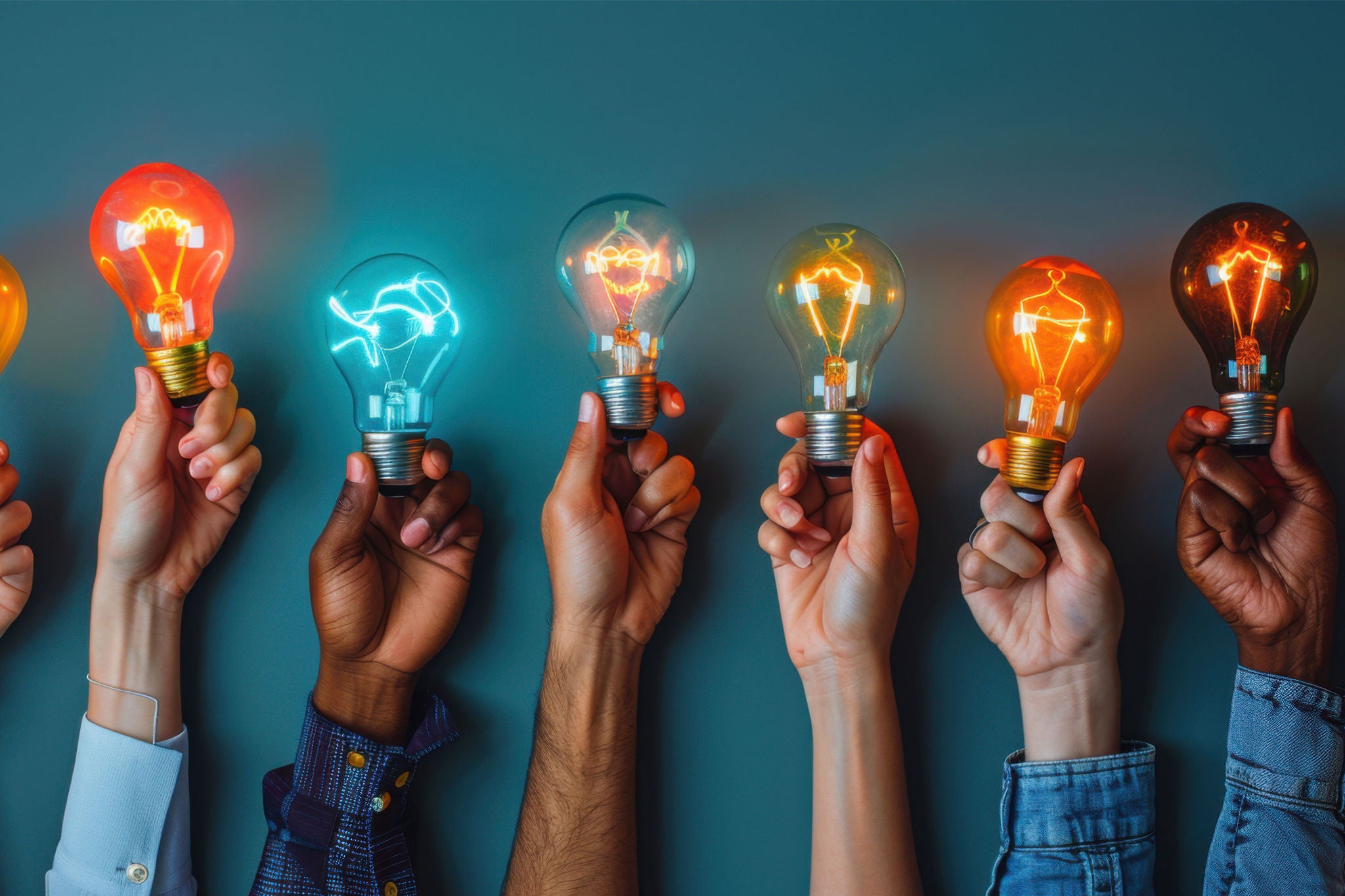 En gruppe hænder holder lyspærere i forskellige farver