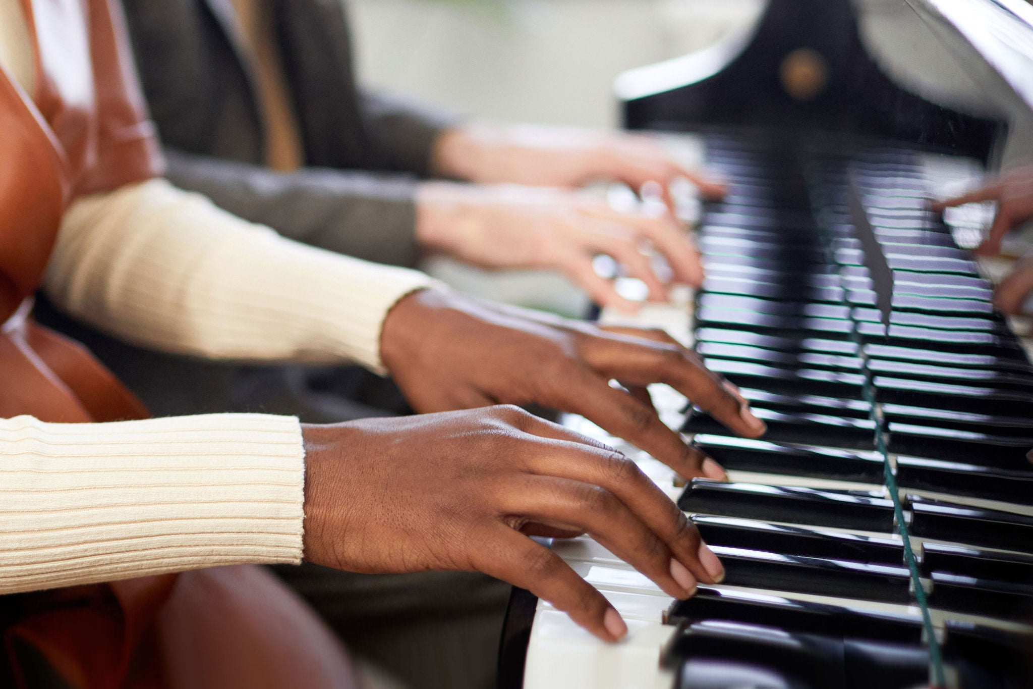 African young woman playing the piano together with her partner in team play during repetition at lesson
