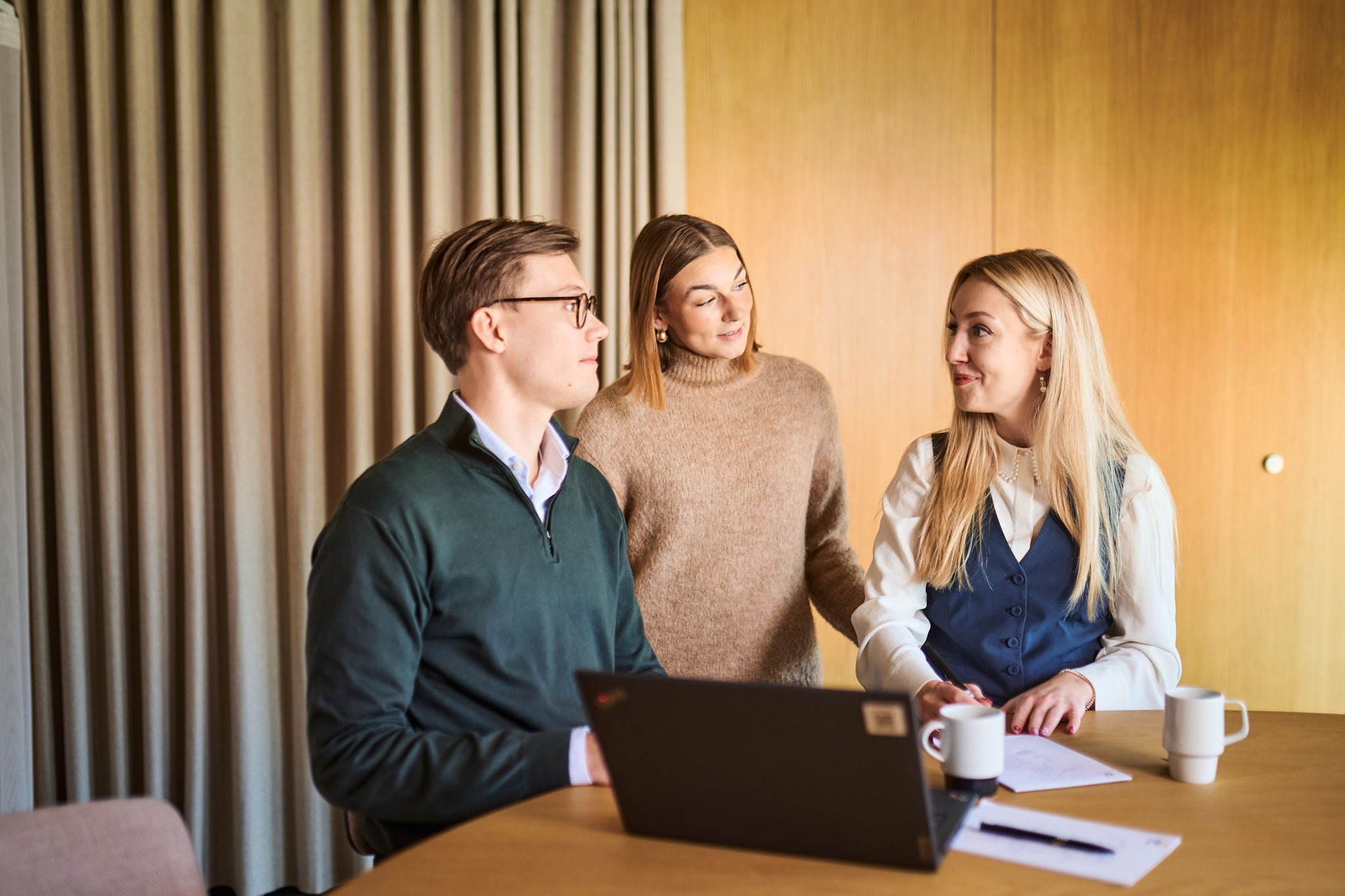 Team discussing ideas together around laptop in modern office setting