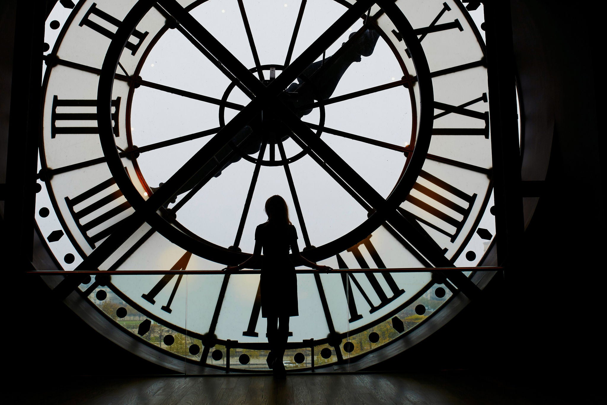 Woman silhouette standing in front of clock in the Orsay Museum, Paris, France. Unrecognizable person overlooking Paris