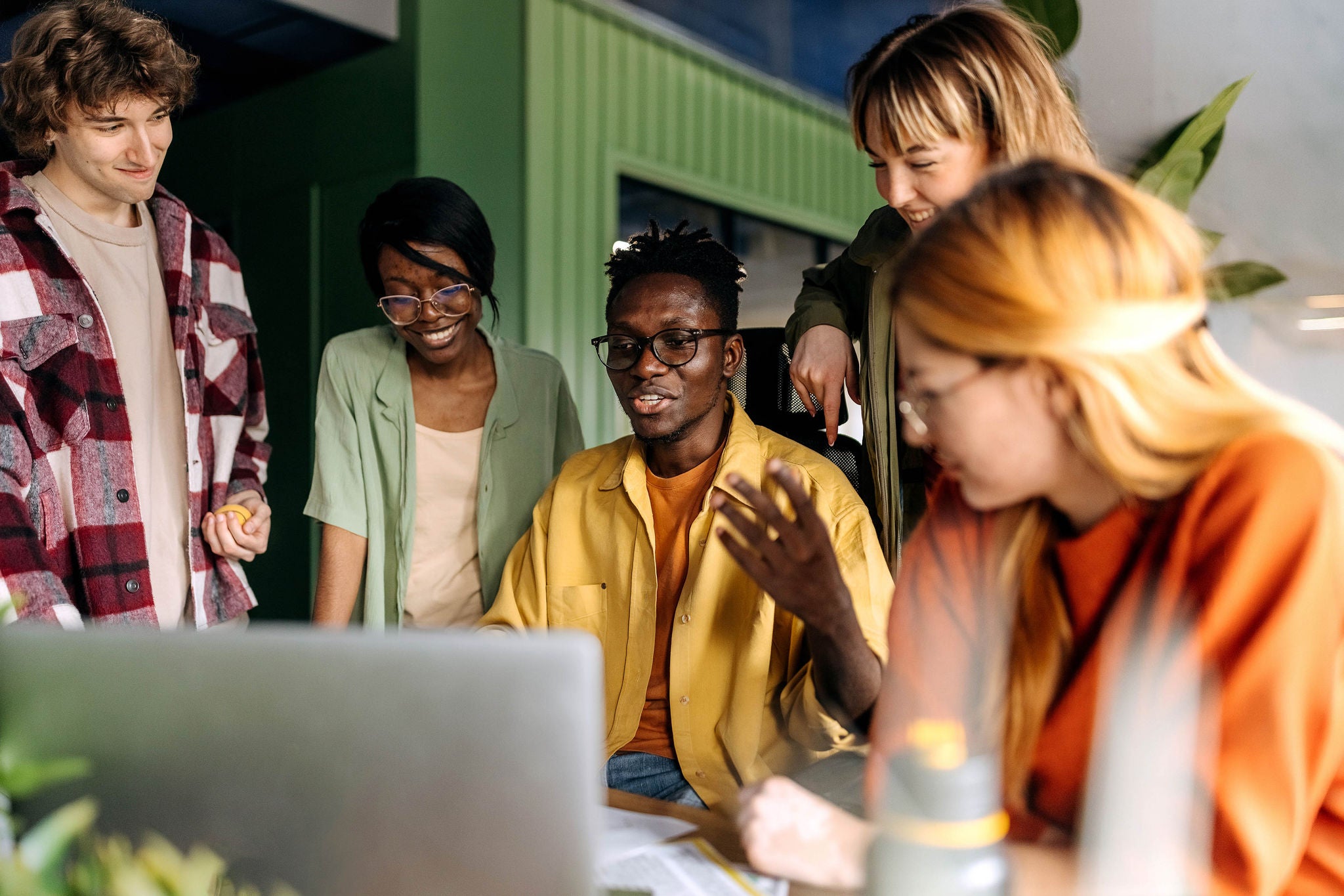 Diverse male and female in a casual office or co-working space interact.