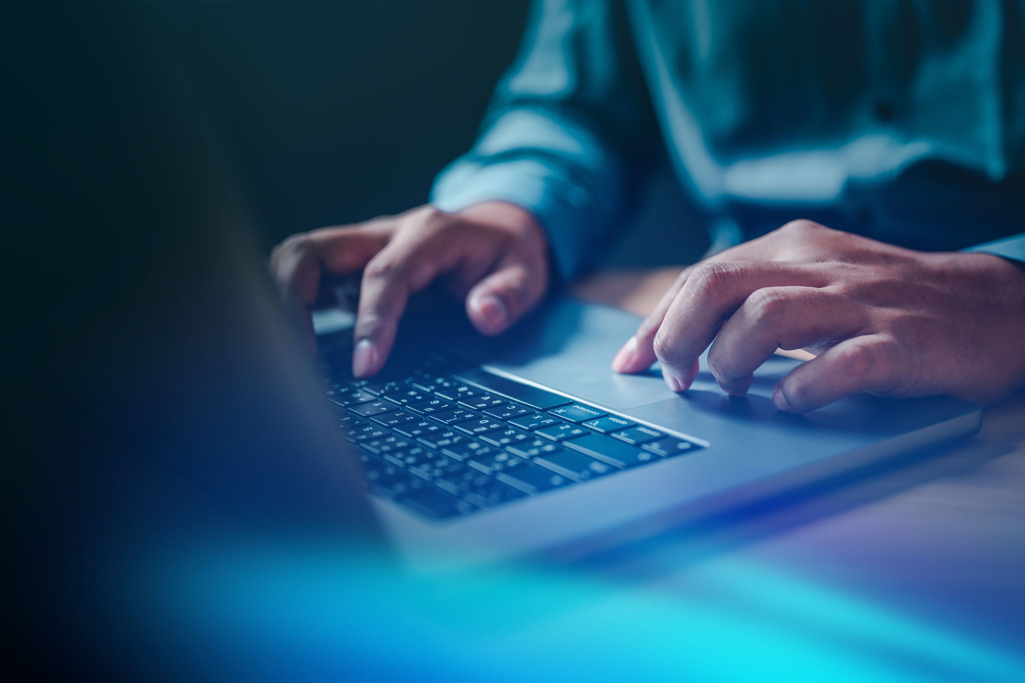 Hands typing on a laptop keyboard in a modern workspace
