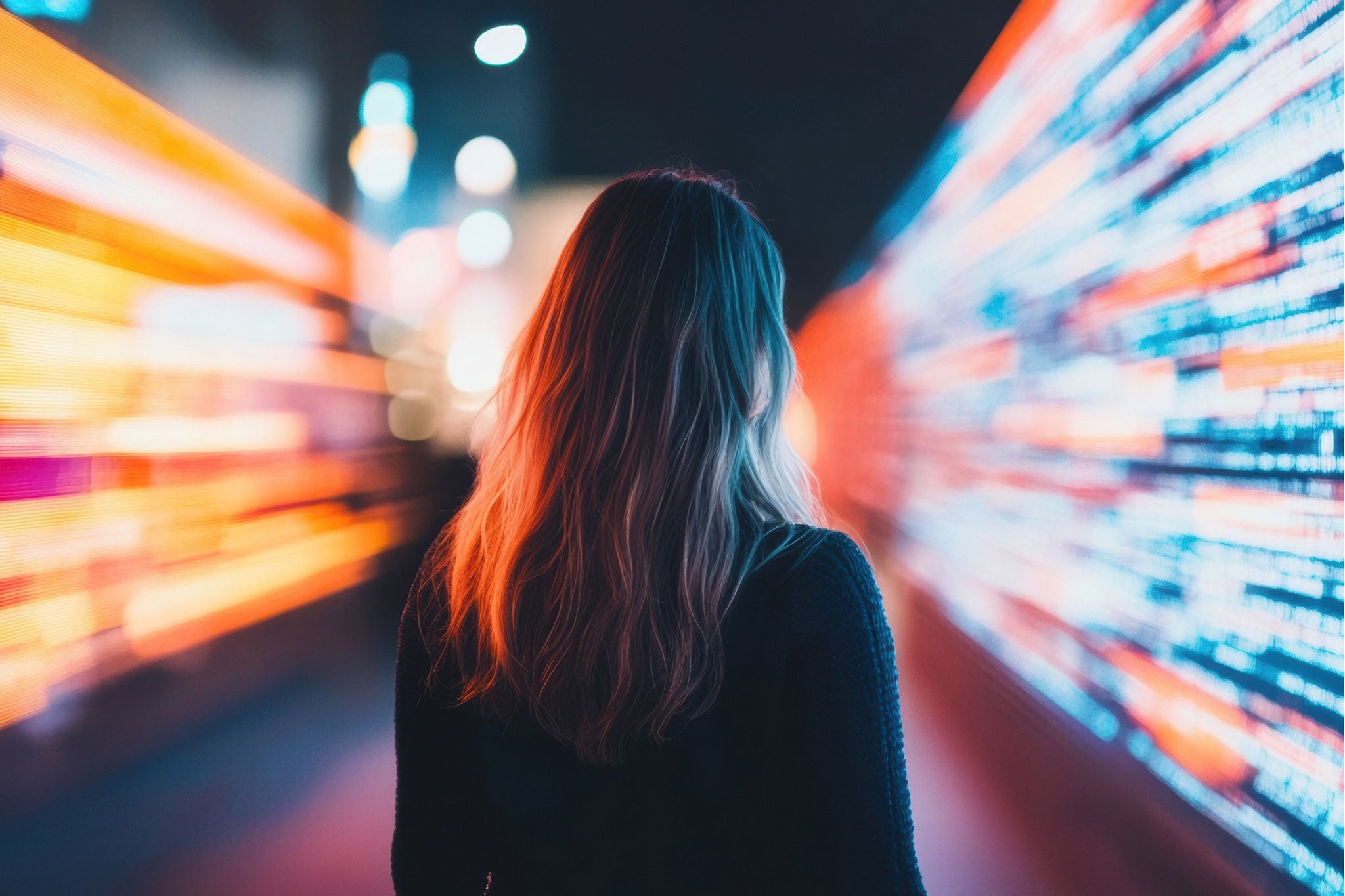 Person walking through vibrant neon lights and digital displays
