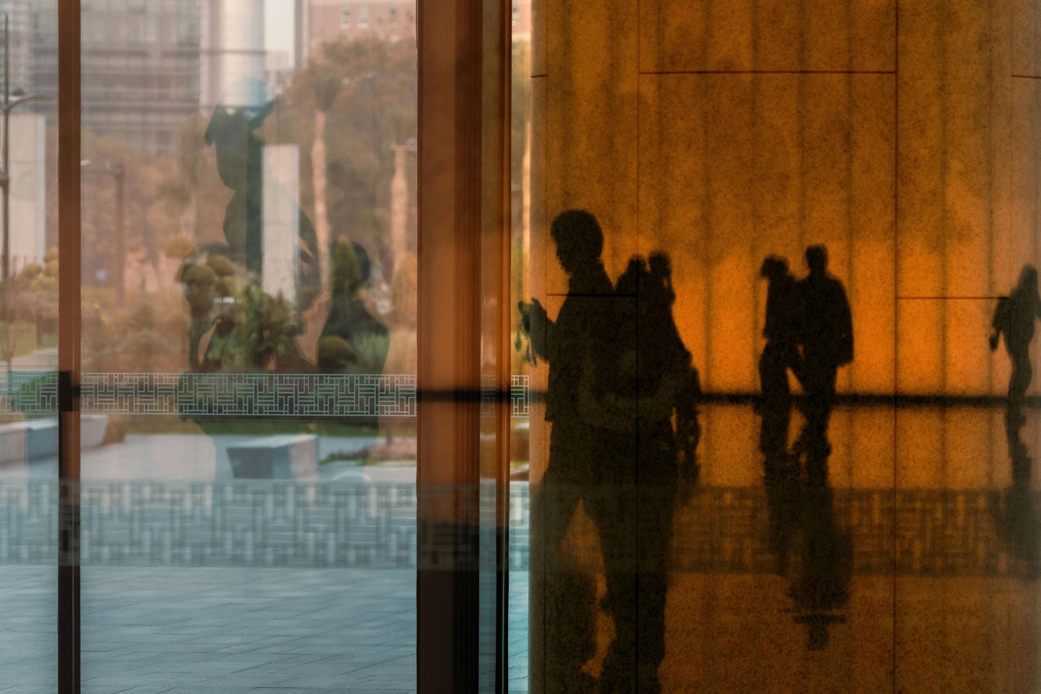 Silhouettes of people reflected on glass surfaces inside a modern building