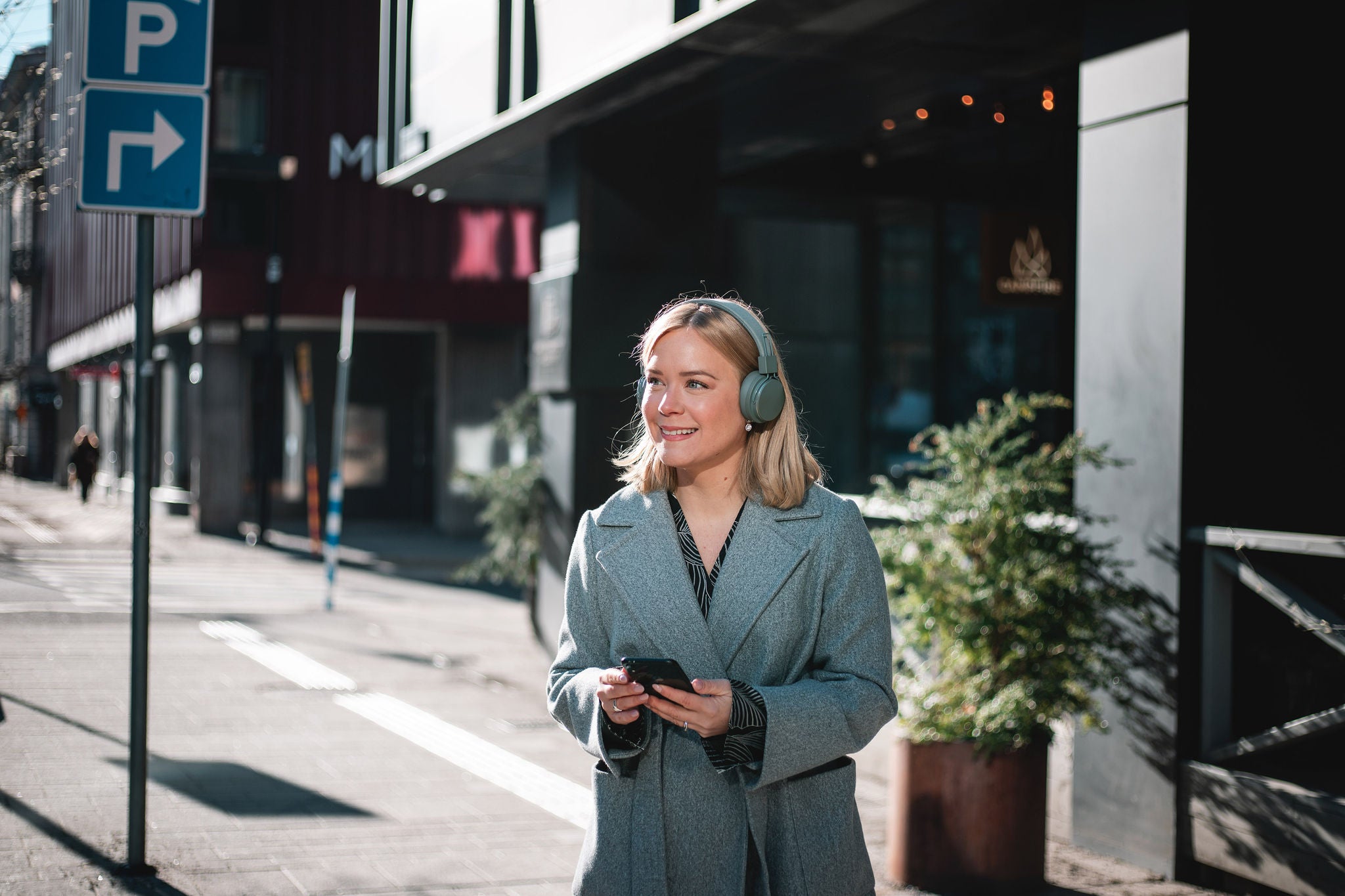 Professional using smartphone with headphones while walking in city