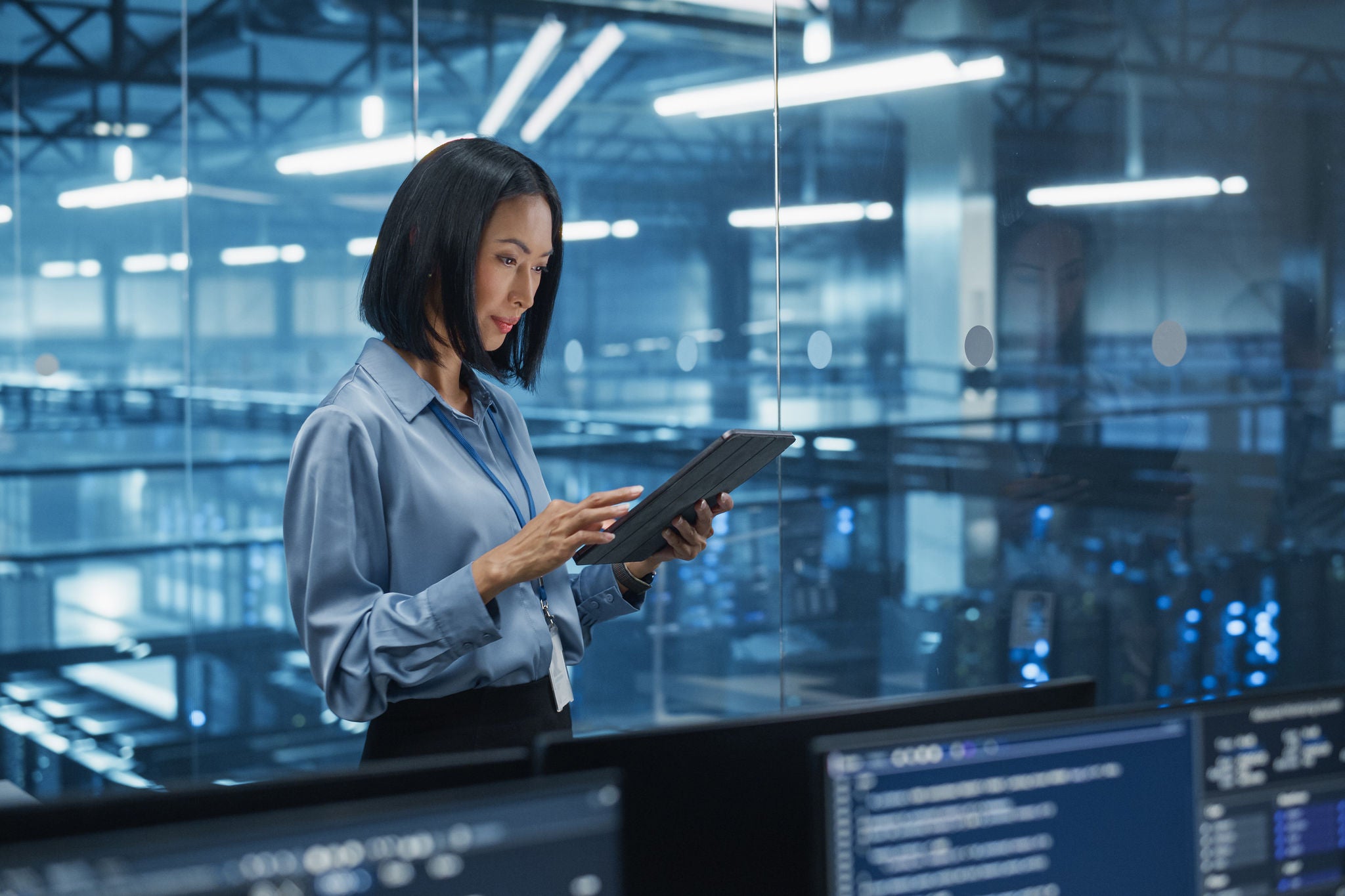 Standing in a modern data center with server systems. Young woman searching for patterns to improve online data flow.