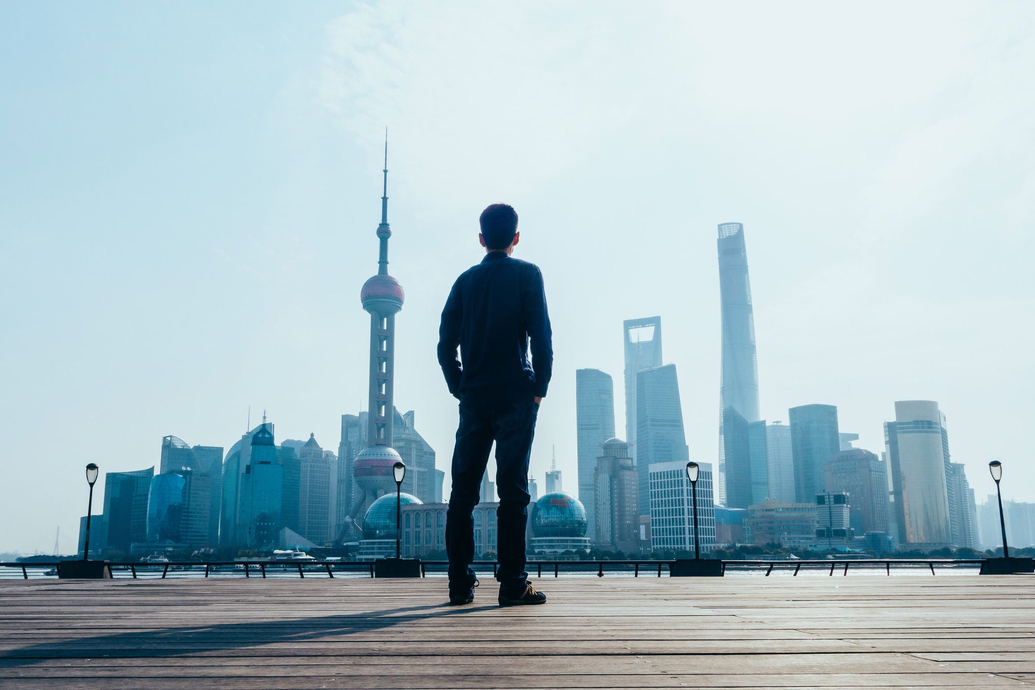 Man standing on a wooden platform looking at a modern city skyline