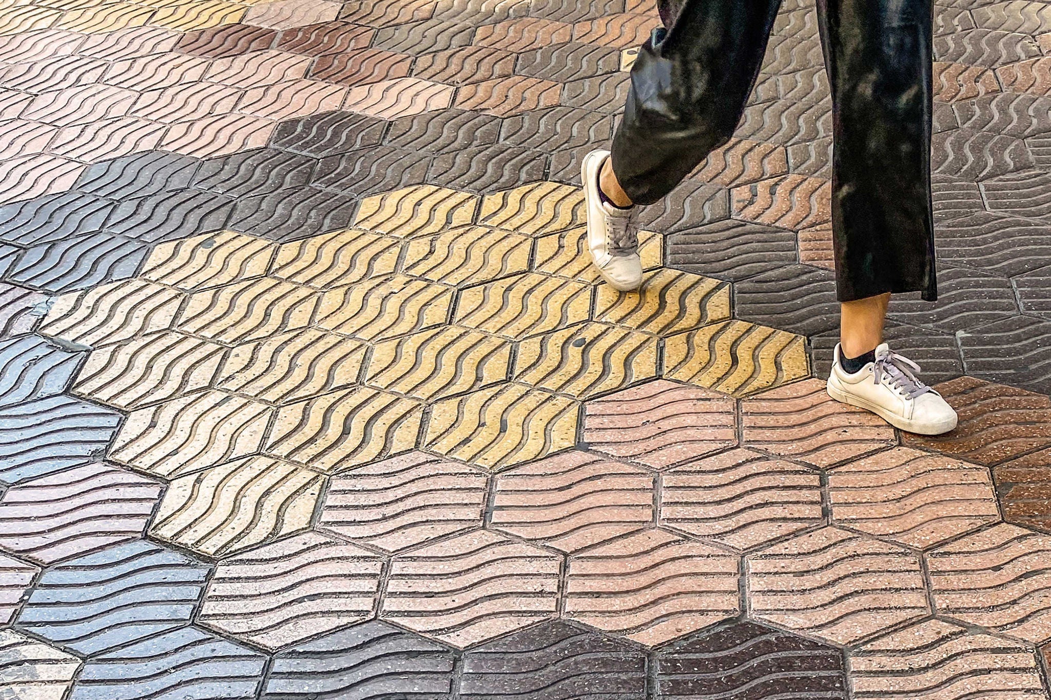 Woman walking over hexagonal tiled floor in the streets of Valencia, Spain