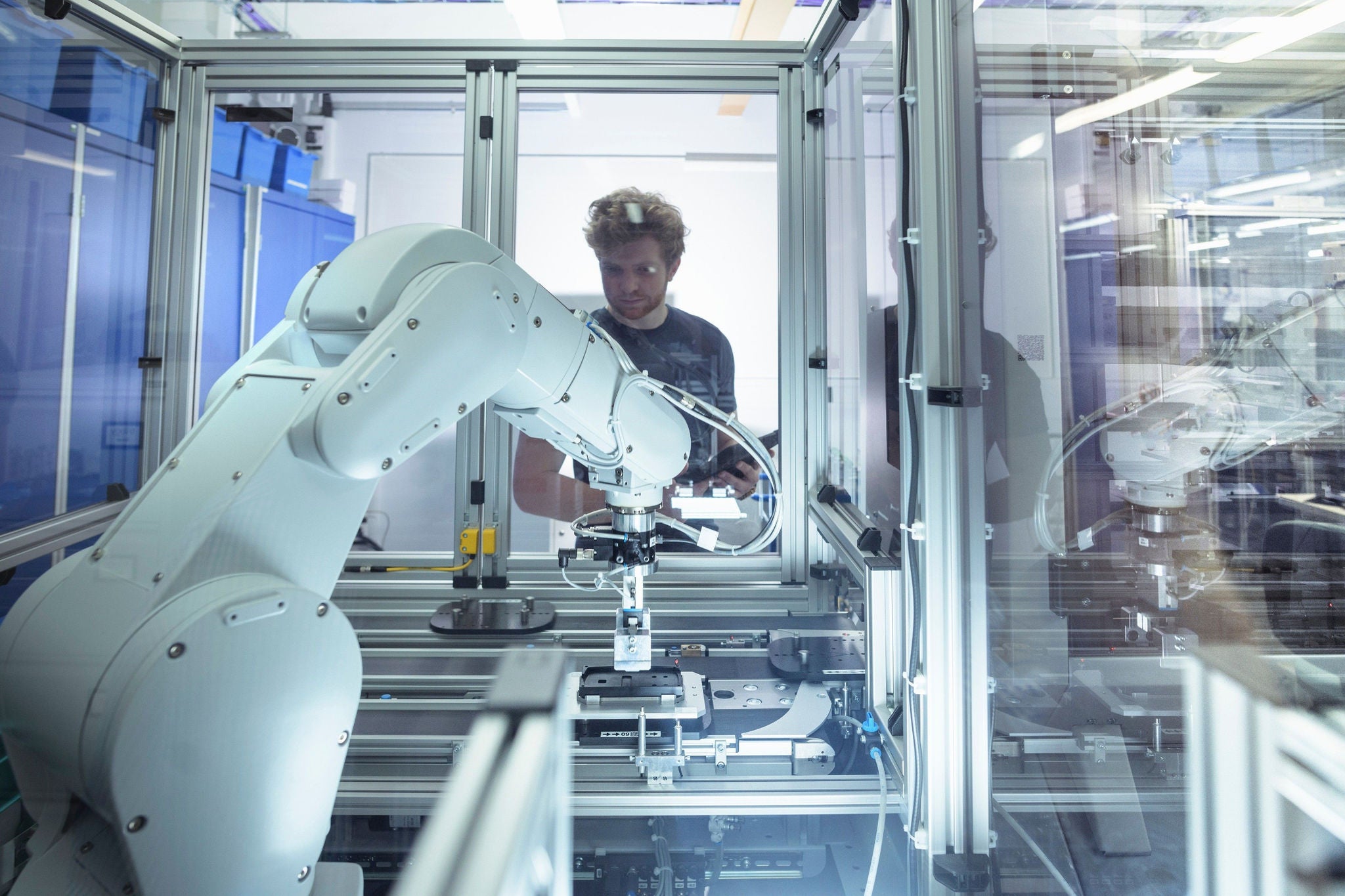 Male trainee engineer with robotic equipment in research facility.