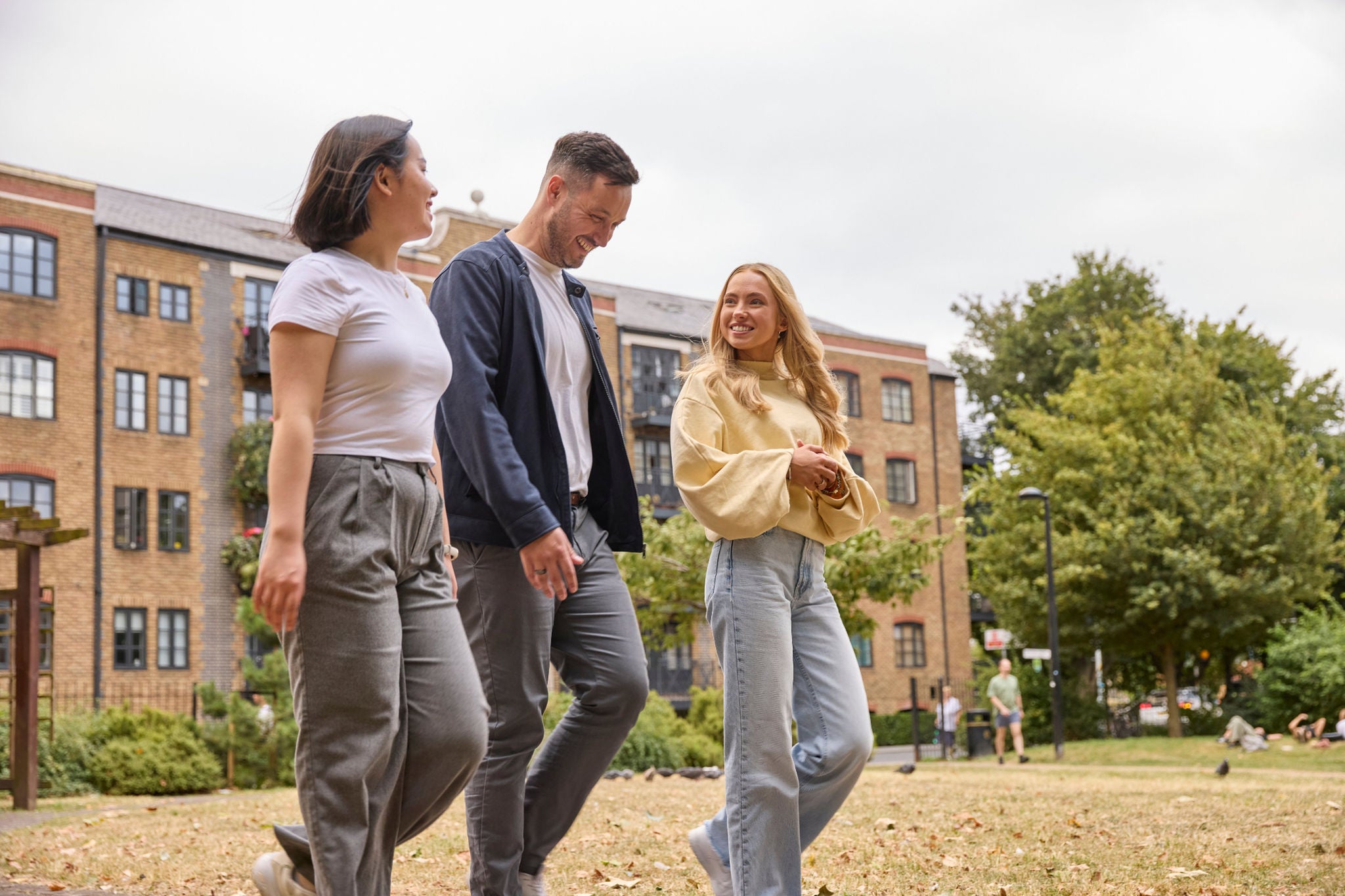 Three colleagues walking together through an urban park