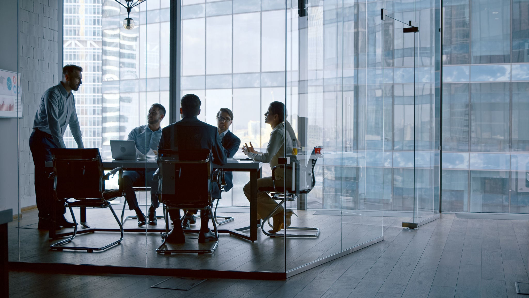 Business people listening the presenter while sitting at desk in meeting room