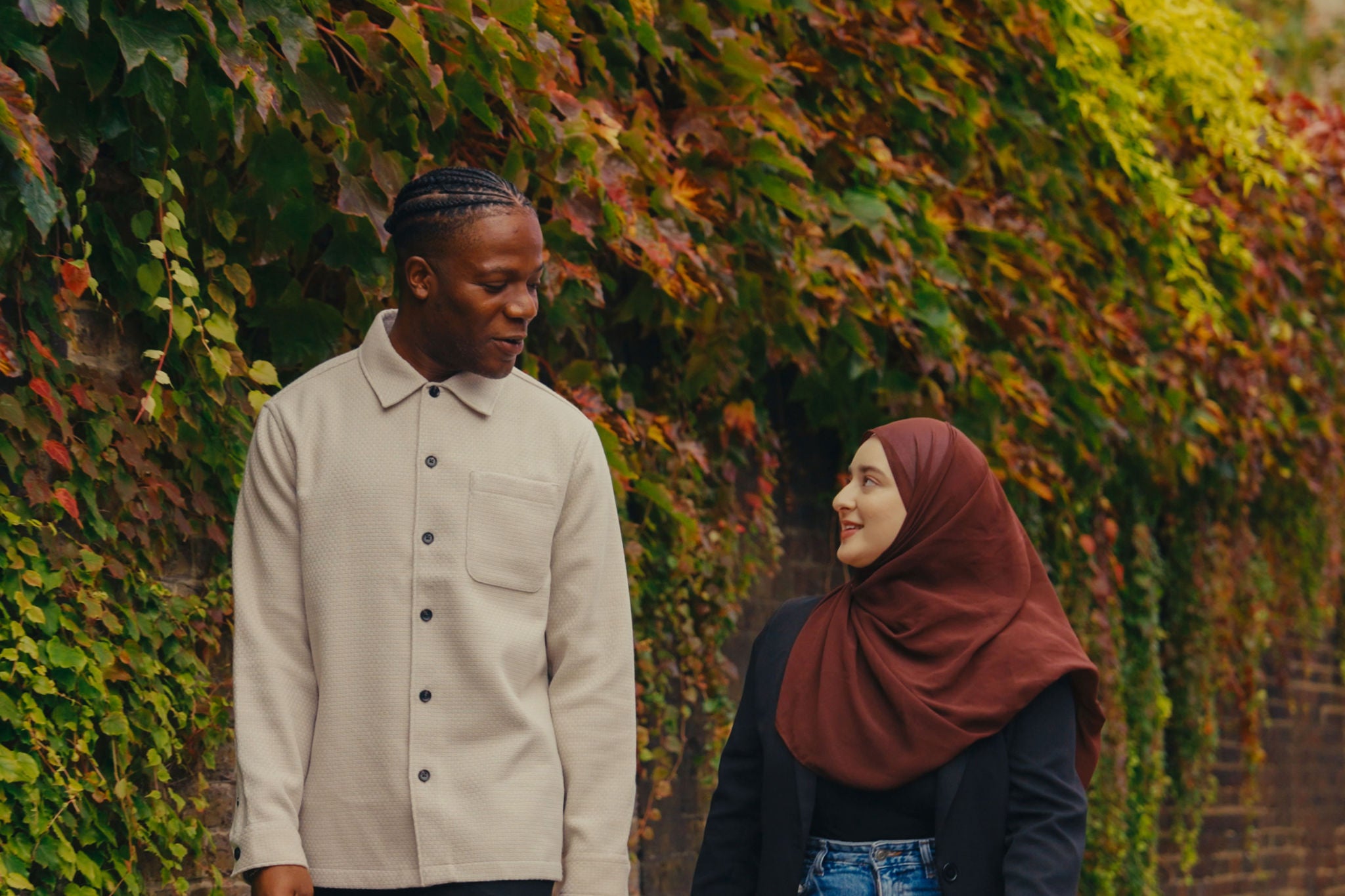 Two colleagues walking past a wall with leaves