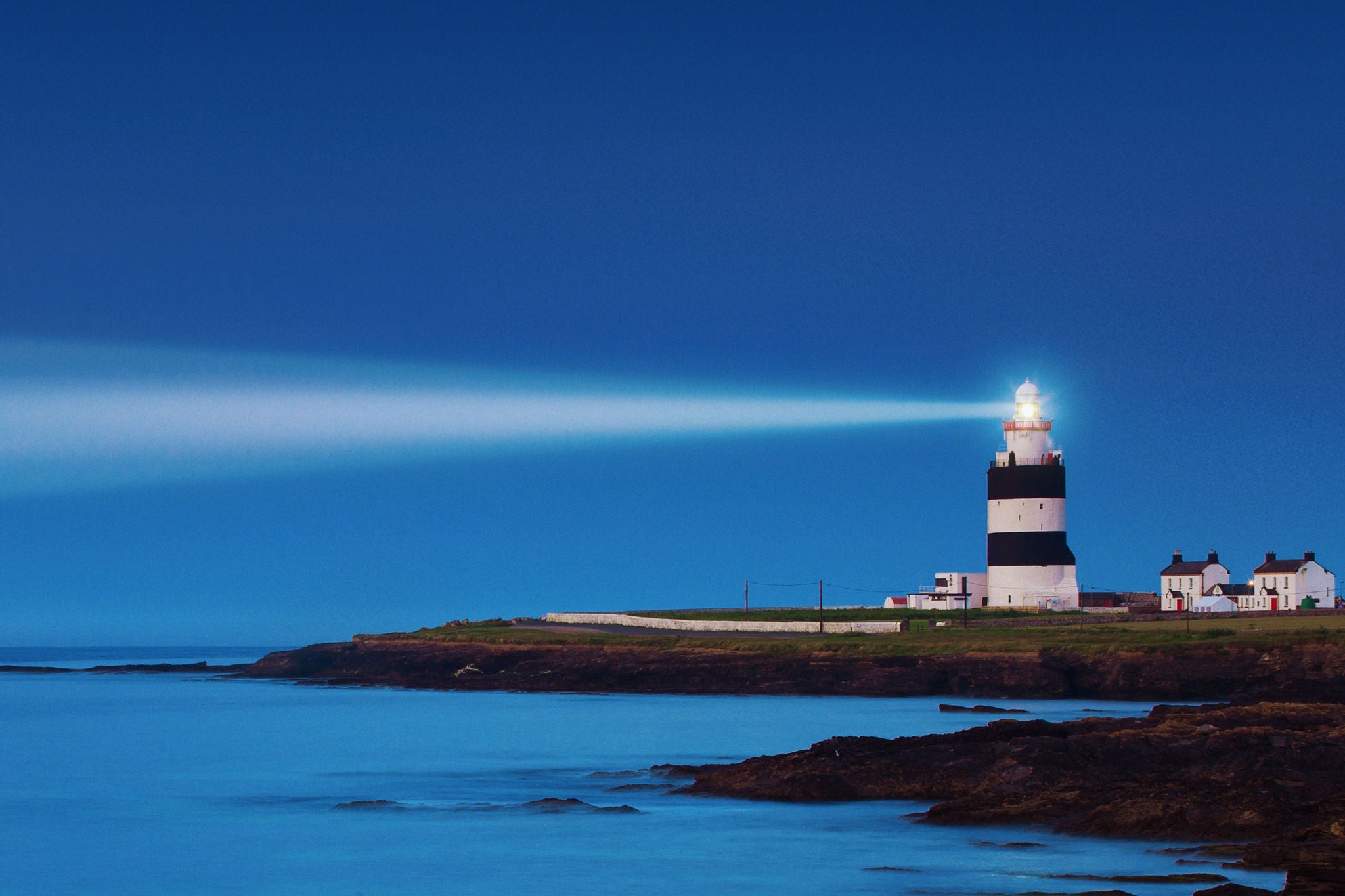Phare diffusant un faisceau lumineux au crepuscule sur la mer