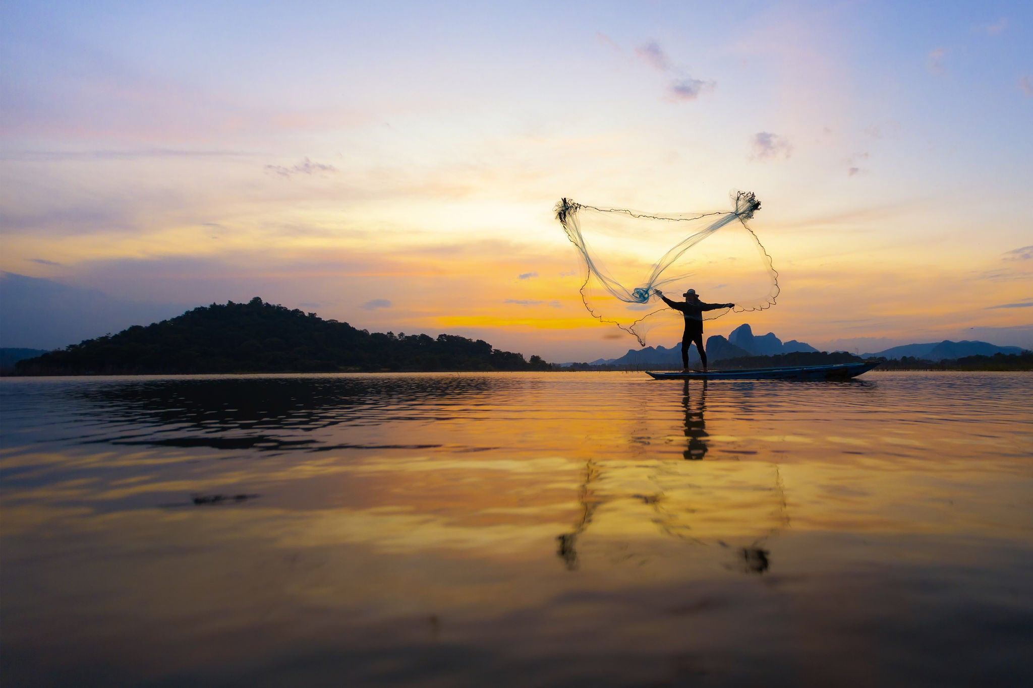 Fisherman throwing fishing nets after sunset