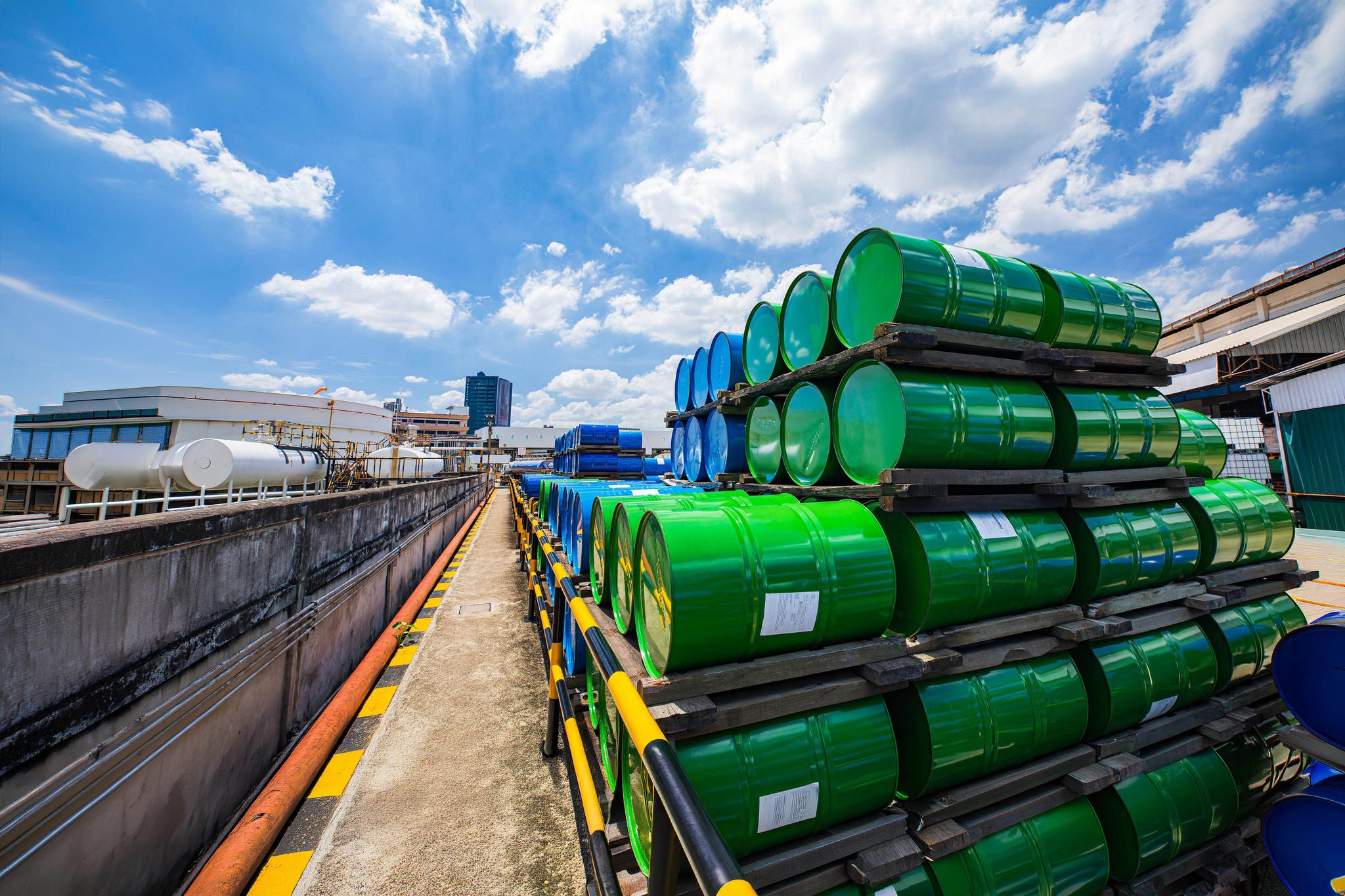 Blue metal barrels of chemical products stacked on pallets in an industrial facility for storage and use onsite