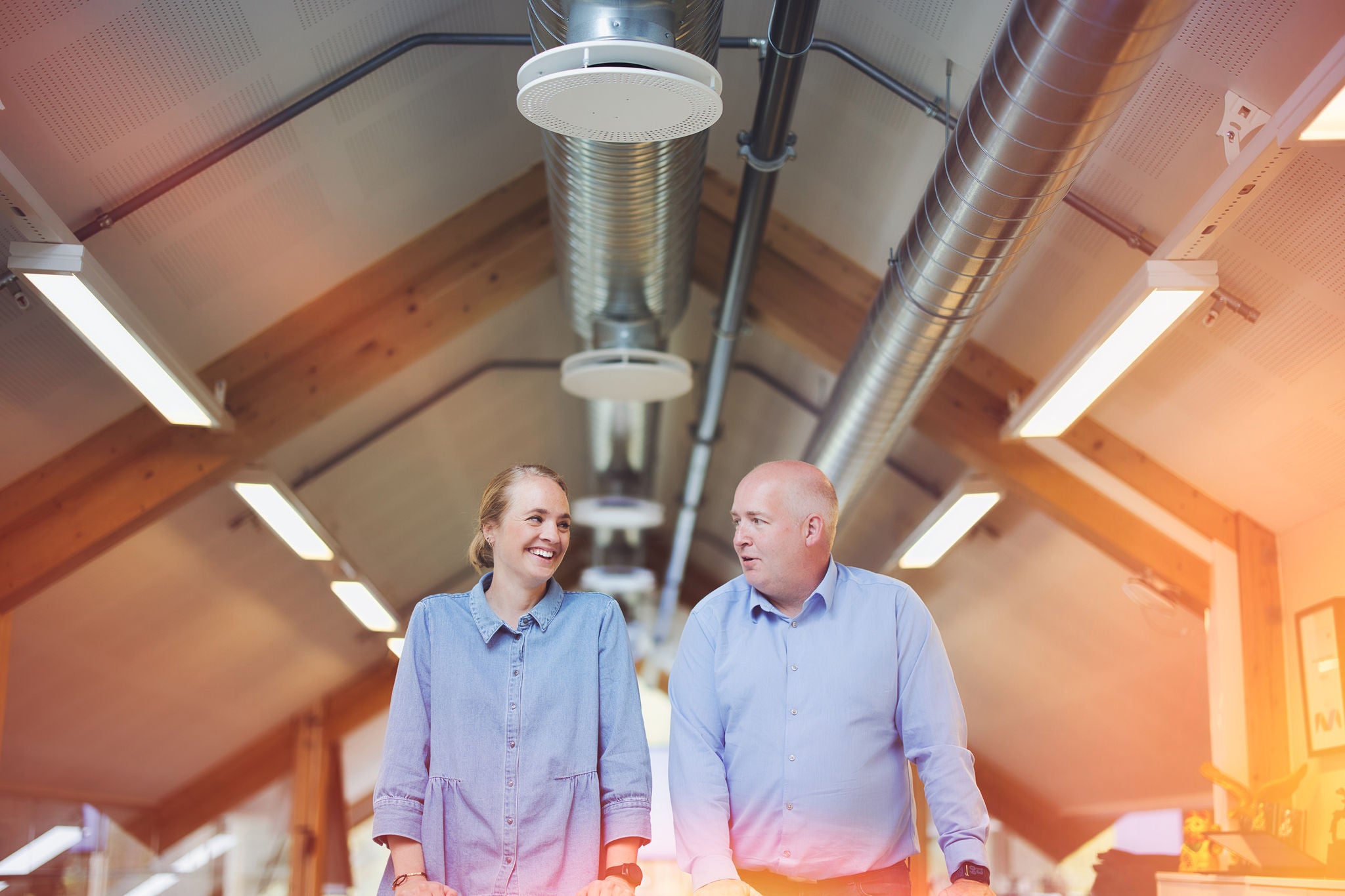 Miriam Melby og Tommy Rugsveen står ved bordet og smiler mens de ser på hverandre.