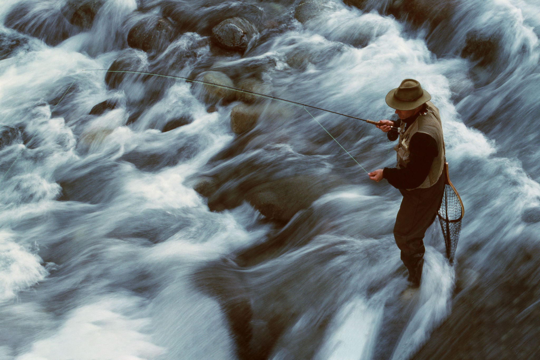 A man stands in a flowing river while fly fishing in Chile, South America.