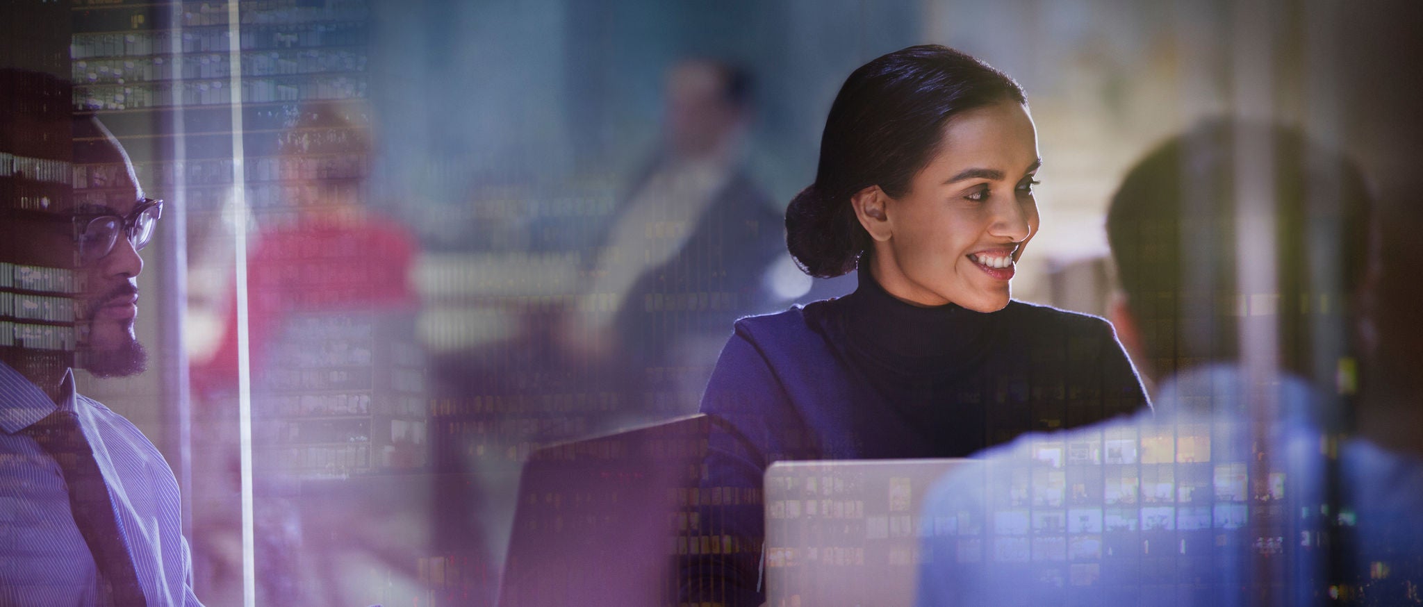 Smiling businesswoman at laptop in meeting in highrise office