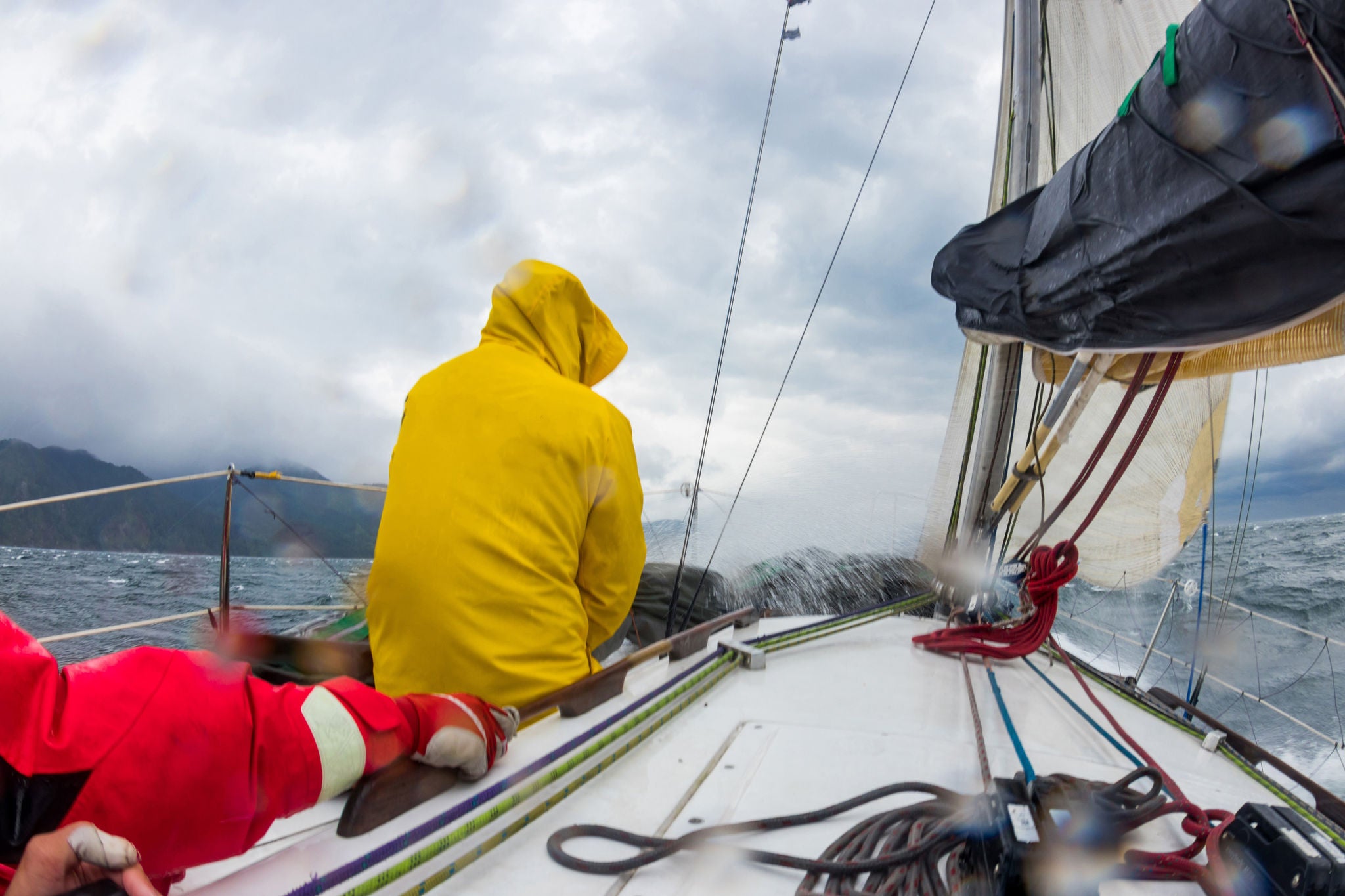 Men work with cord of sails of a yacht in the difficult storm sea
