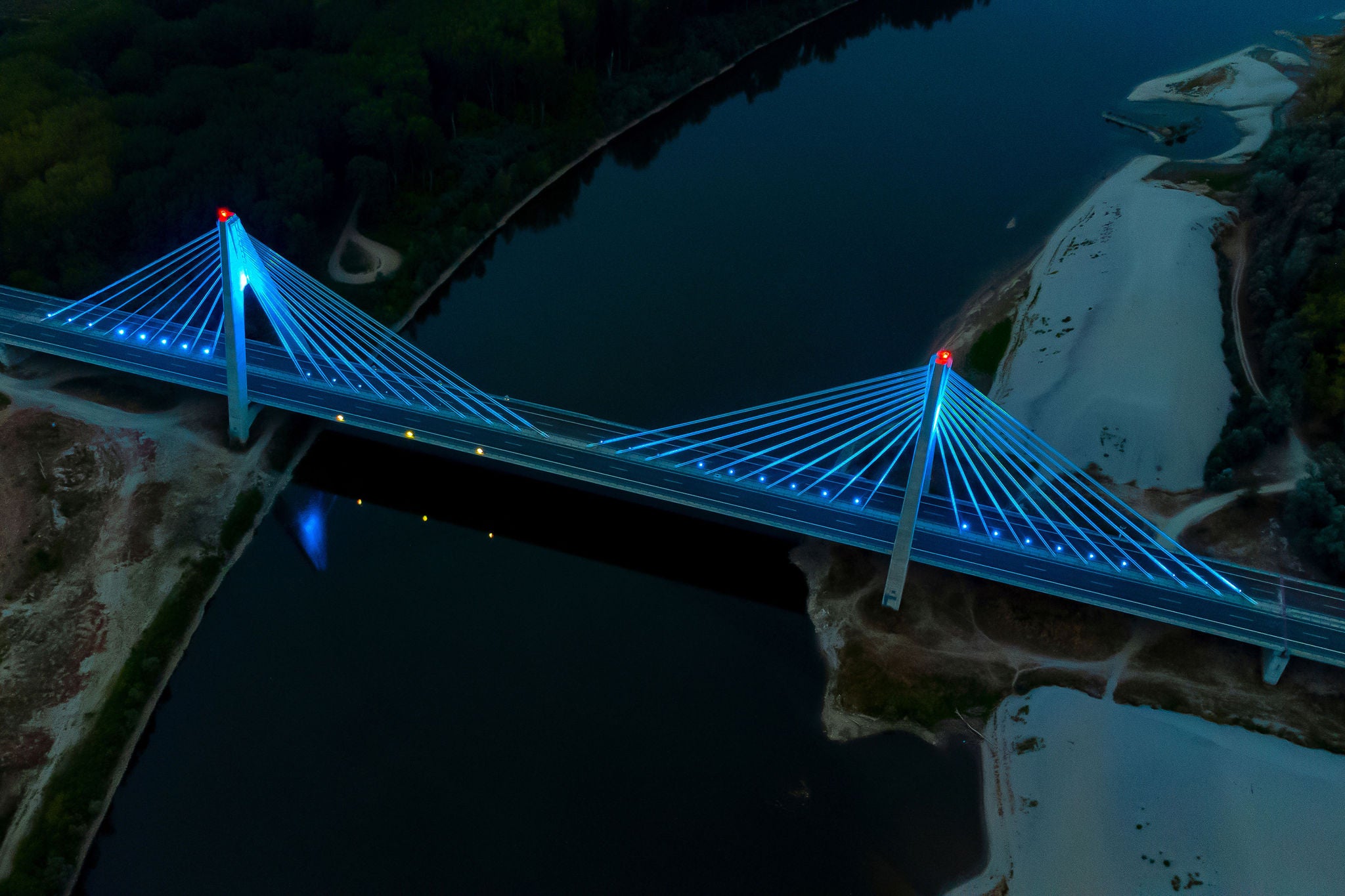 Vue aérienne nocturne d’un pont à haubans illuminé en bleu