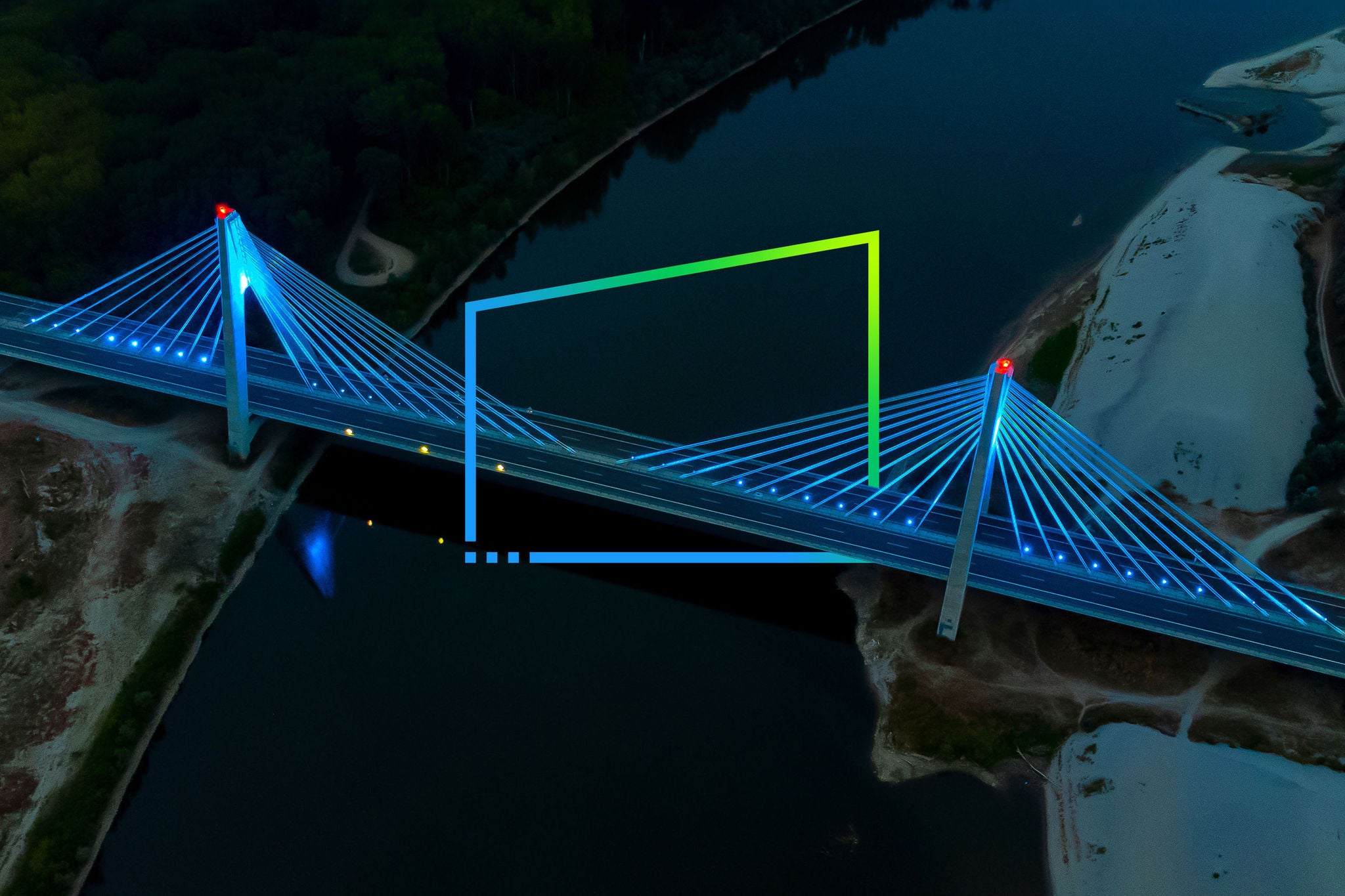Aerial view of the illuminated cable stayed bridge over the dark river 
