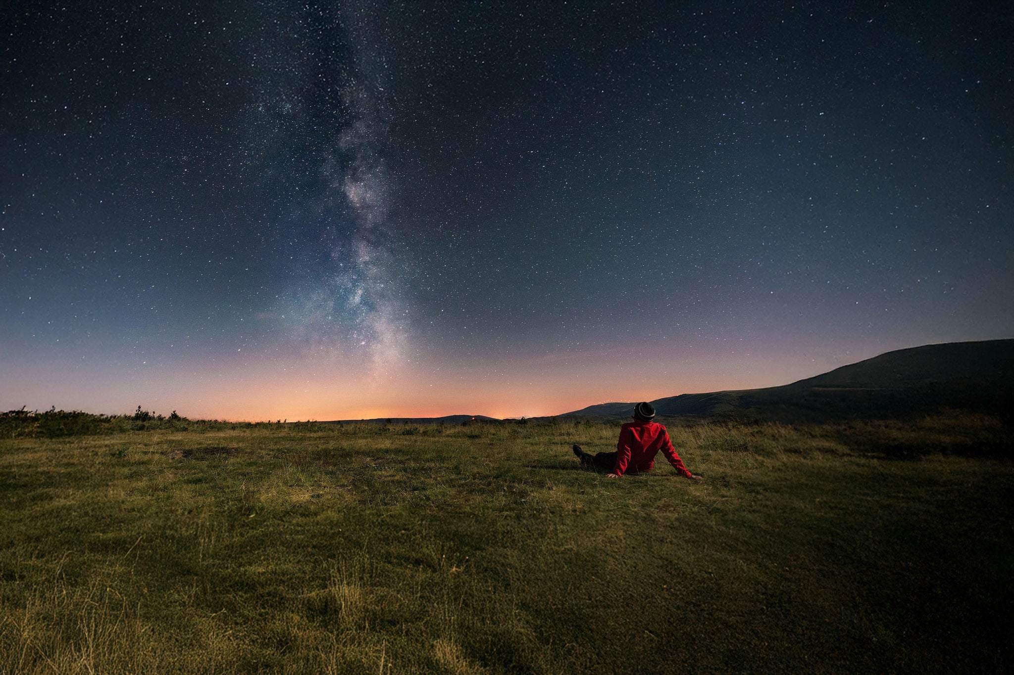 A young man lying on the grass and watching the Milky Way