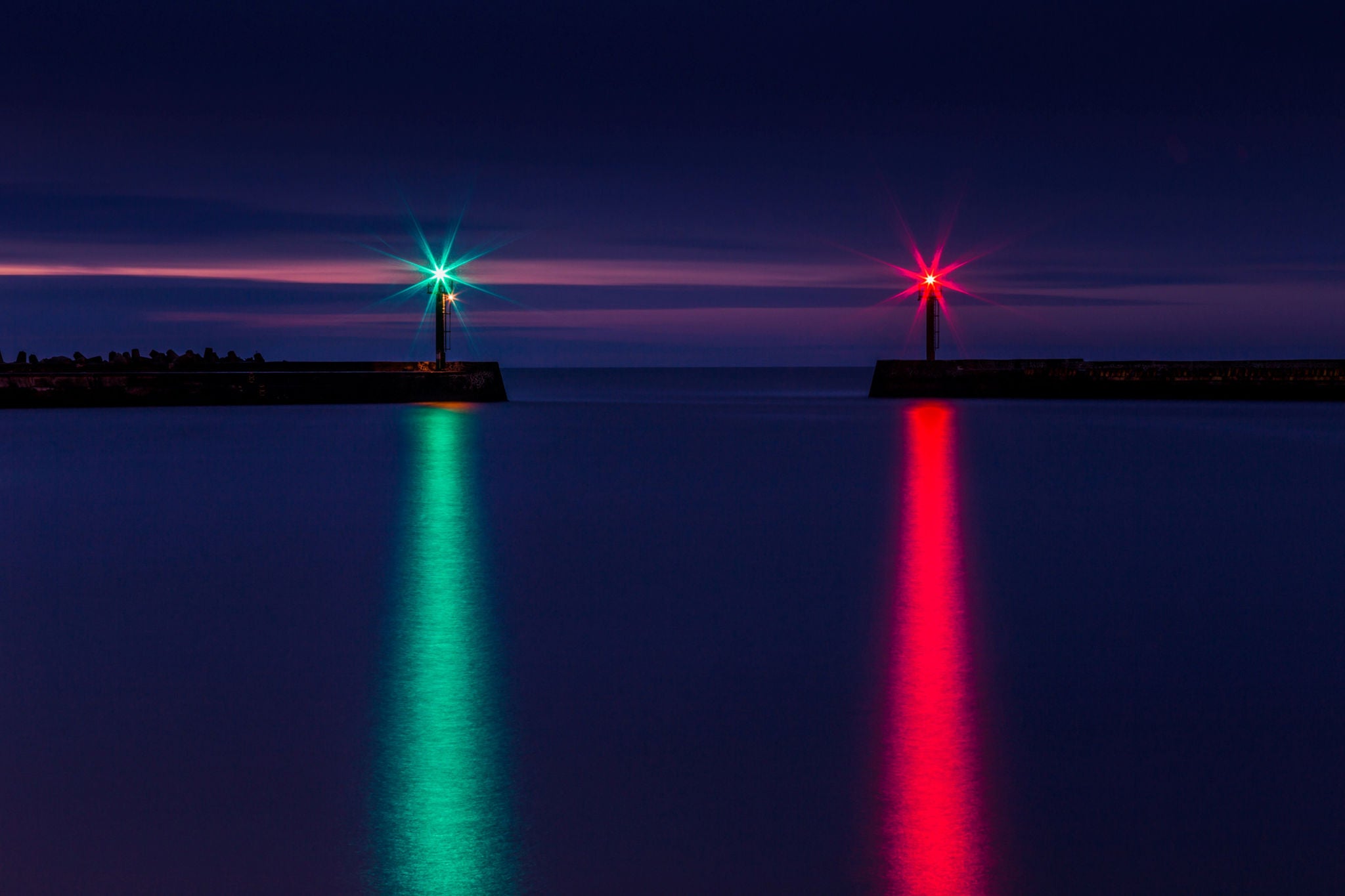 Navigation lights reflecting on calm harbour waters at night